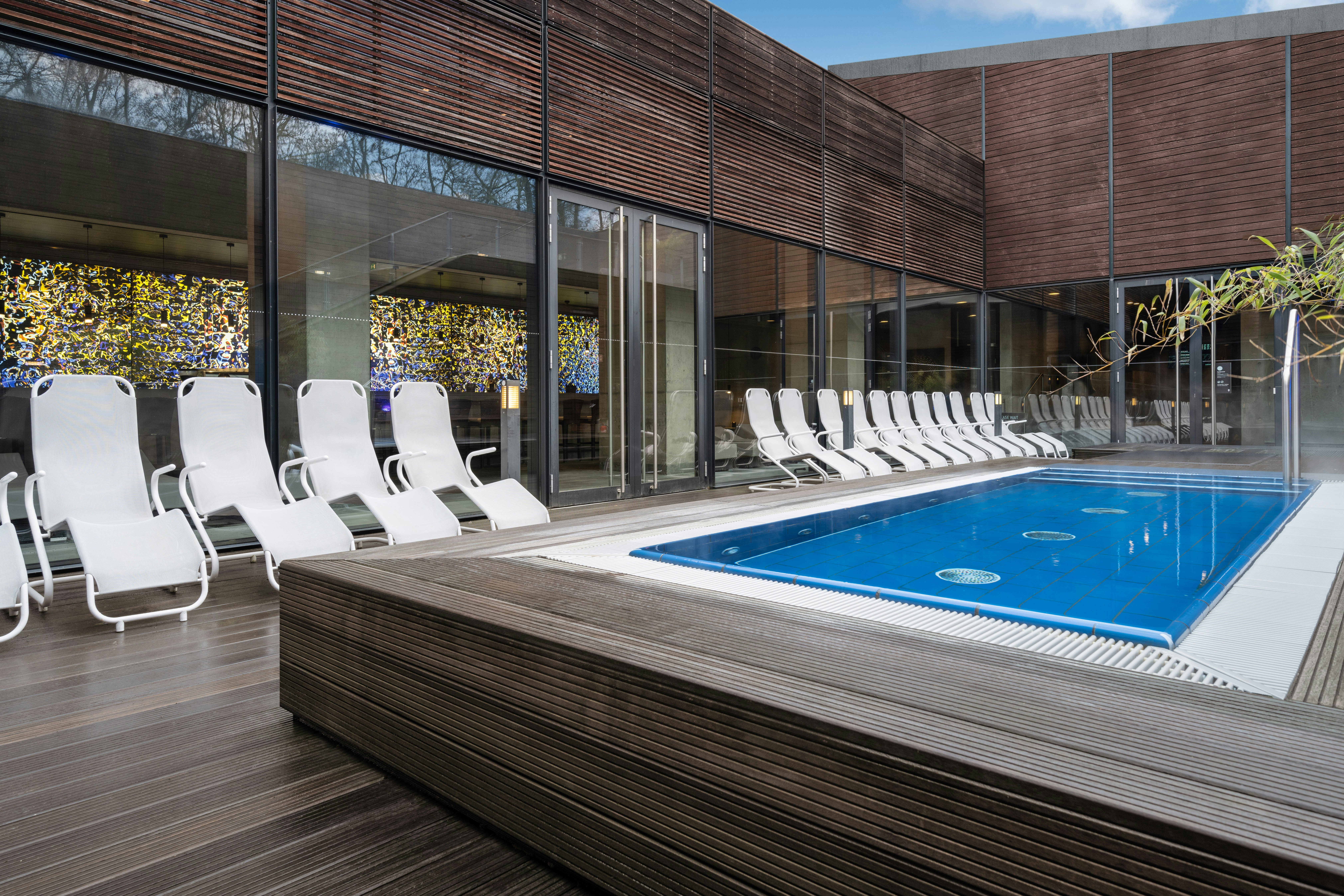 A pool terrace with a small rectangular pool with several loungers around the outside.