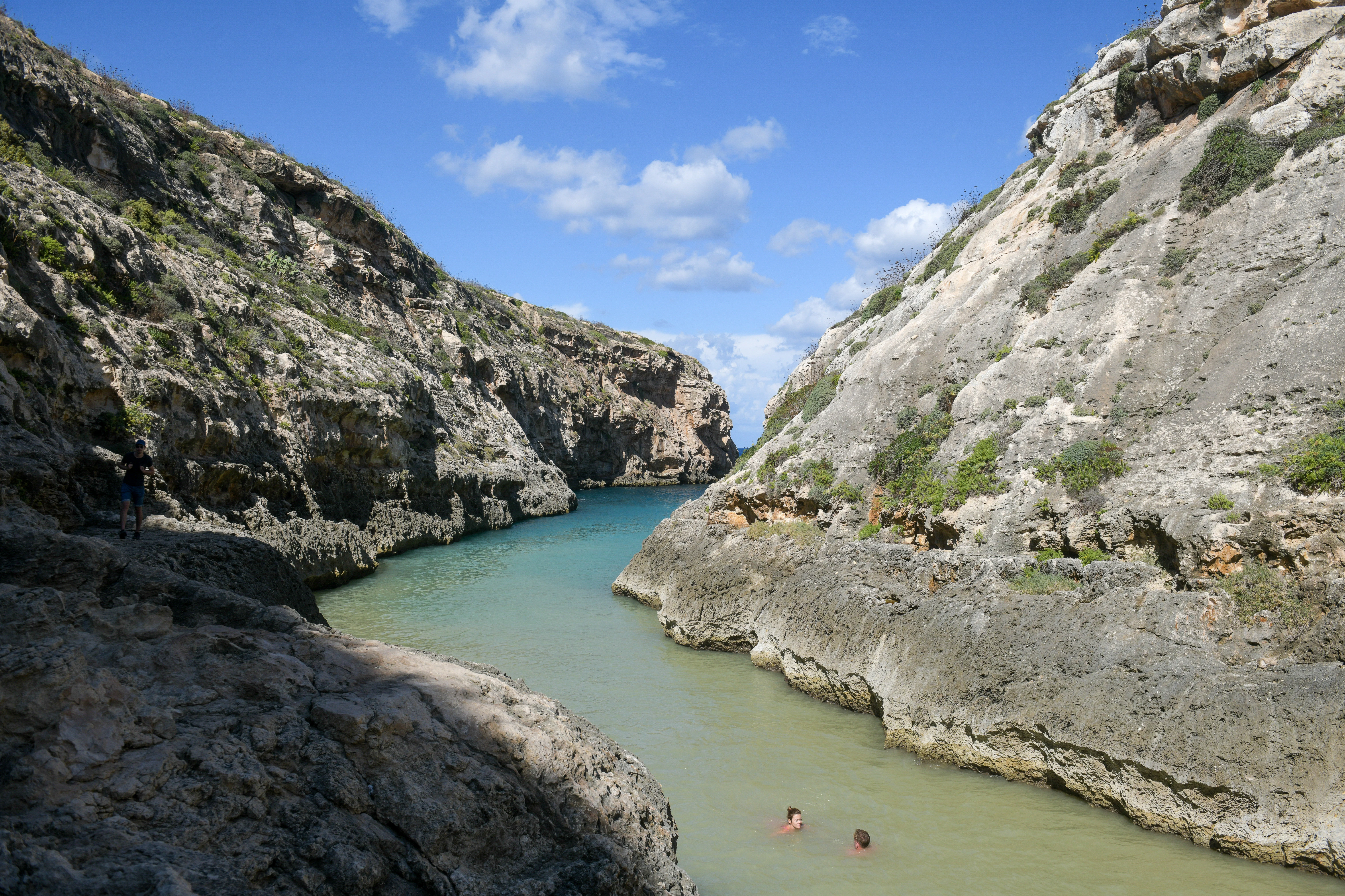 Two people in a river with large rocks on either side