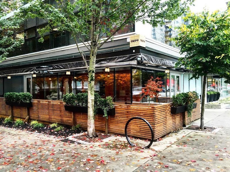 The exterior of a corner bar with wooden barriers creating a terrace that's separate to the sidewalk.
