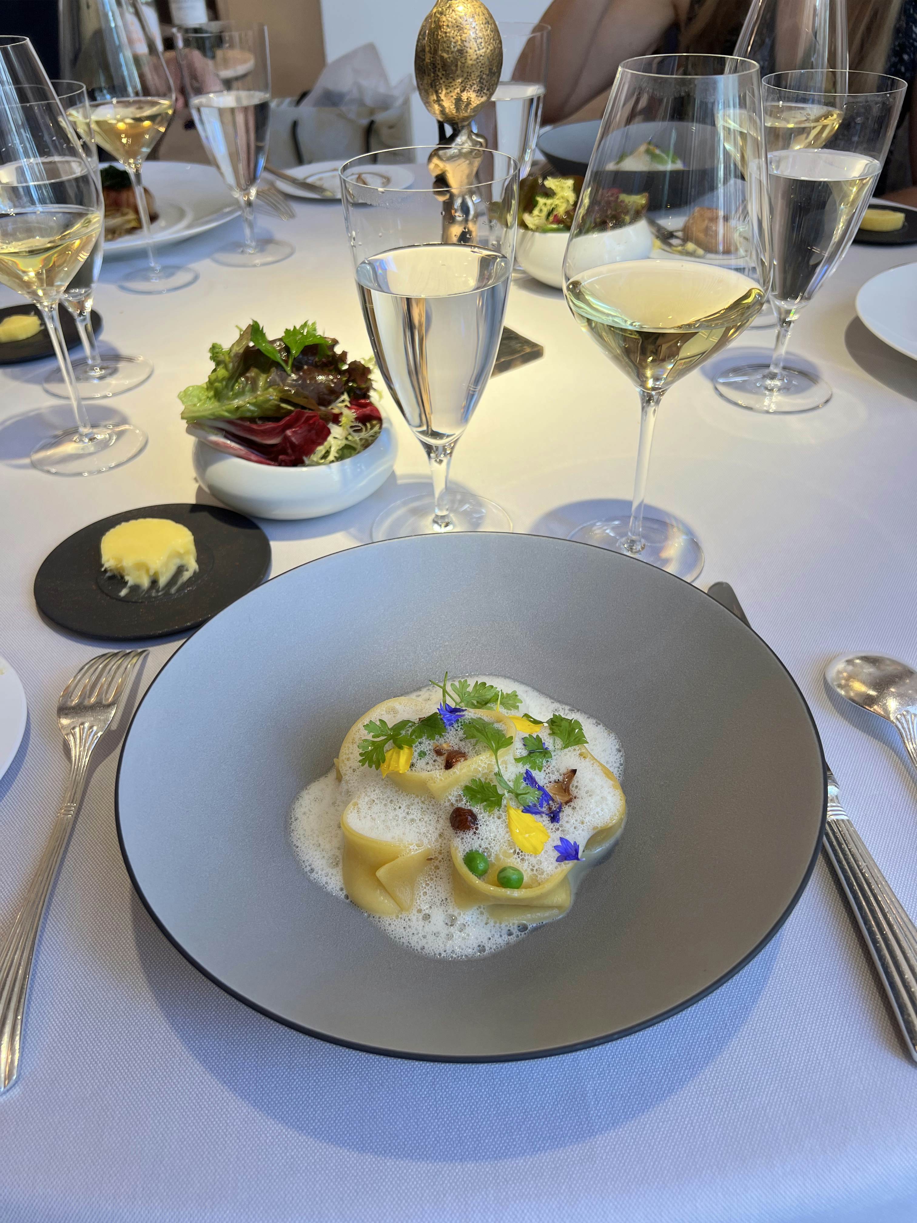 A grey round dish with a pasta in a foamy sauce. 