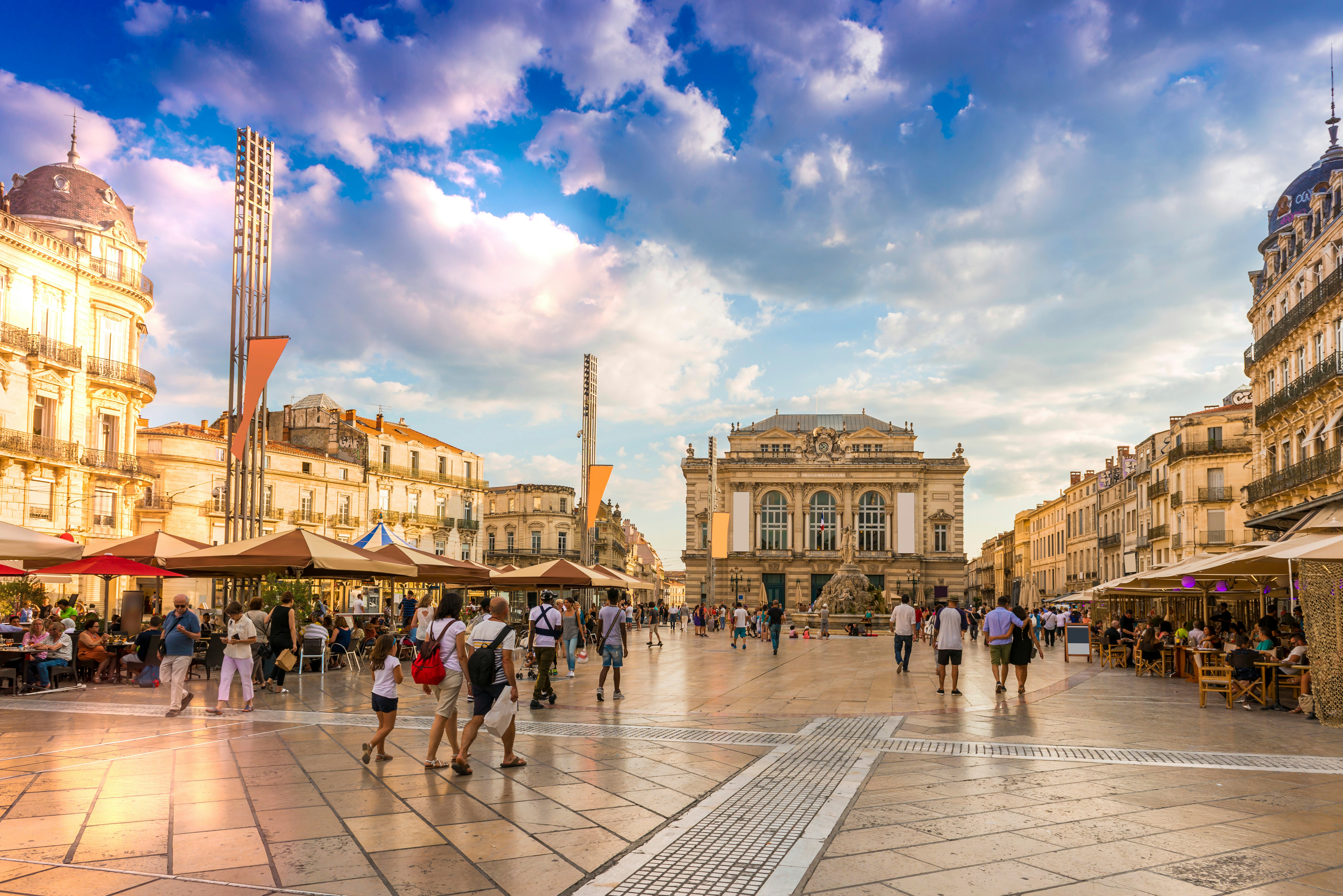 People strolling through a pedestrianized city square in the evening sunshine.