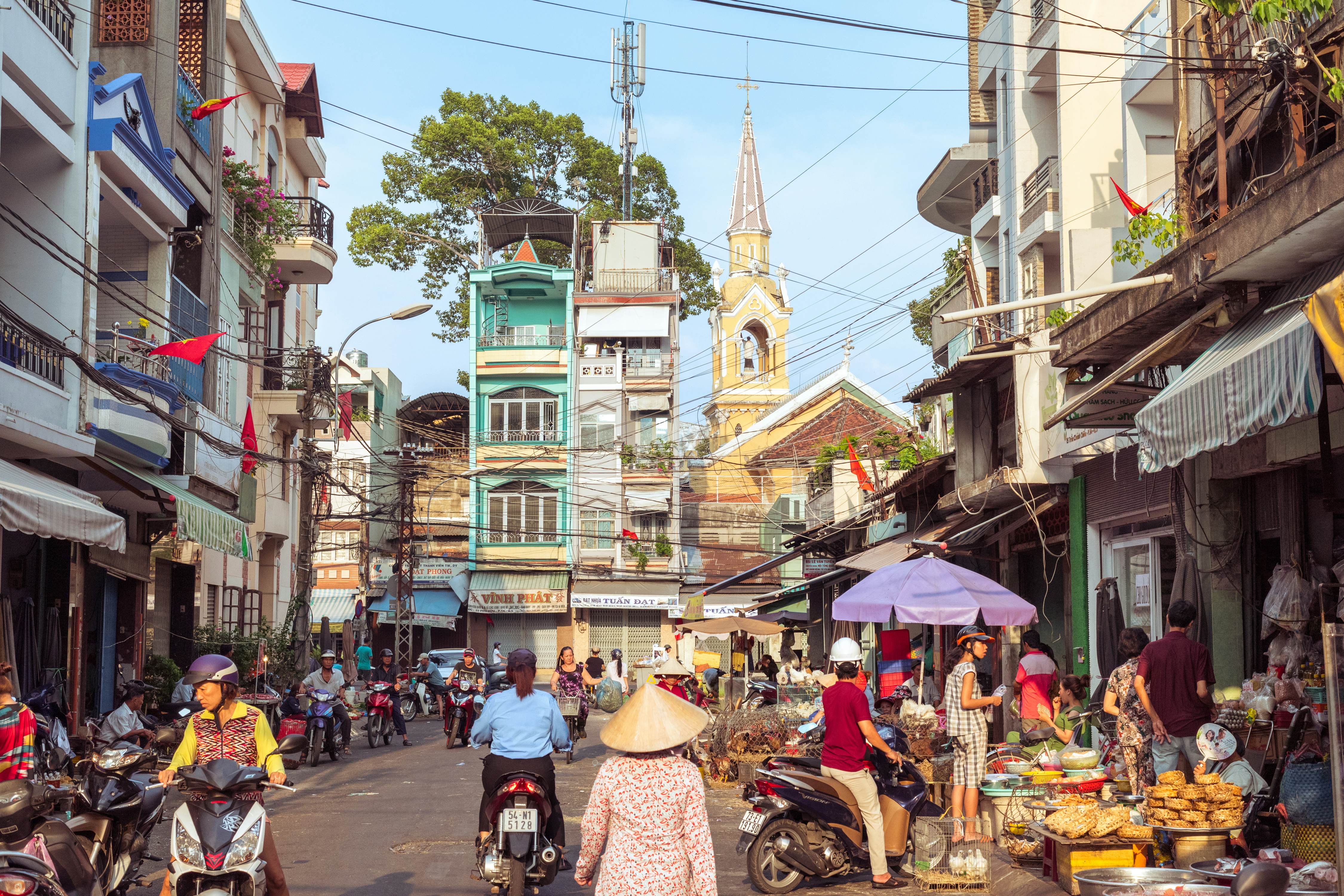Ho Chi Minh City, Vietnam - May 1, 2019: a picturesque street of Cholon occupied by market activity, with a view of townhouses and Cha Tam Church (St. Francis Xavier Parish Church).  License Type: media  Download Time: 2023-04-12T12:32:53.000Z  User: nic.dhoedt_lonelyplanet  Is Editorial: Yes  purchase_order:   