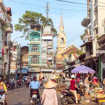 Ho Chi Minh City, Vietnam - May 1, 2019: a picturesque street of Cholon occupied by market activity, with a view of townhouses and Cha Tam Church (St. Francis Xavier Parish Church). License Type: media Download Time: 2023-04-12T12:32:53.000Z User: nic.dhoedt_lonelyplanet Is Editorial: Yes purchase_order: