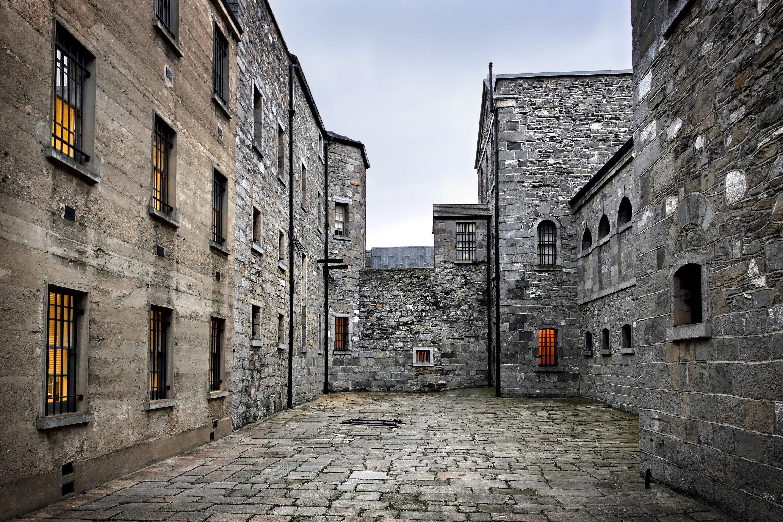 The stone-paved courtyard of old stone prison, surrounded by massive stone walls.