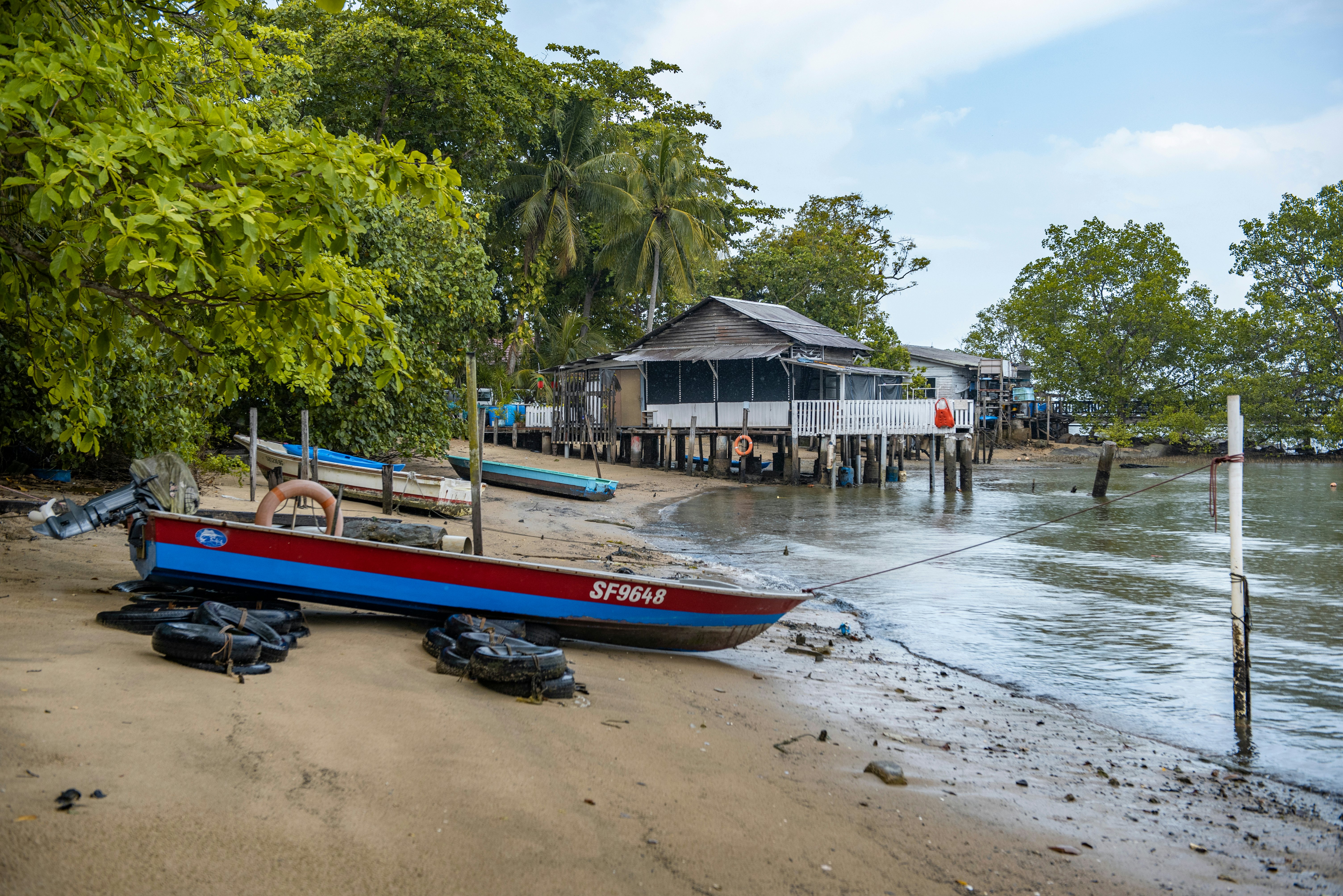 A boat sits on the sand of a beach in a cove on a tropical island.