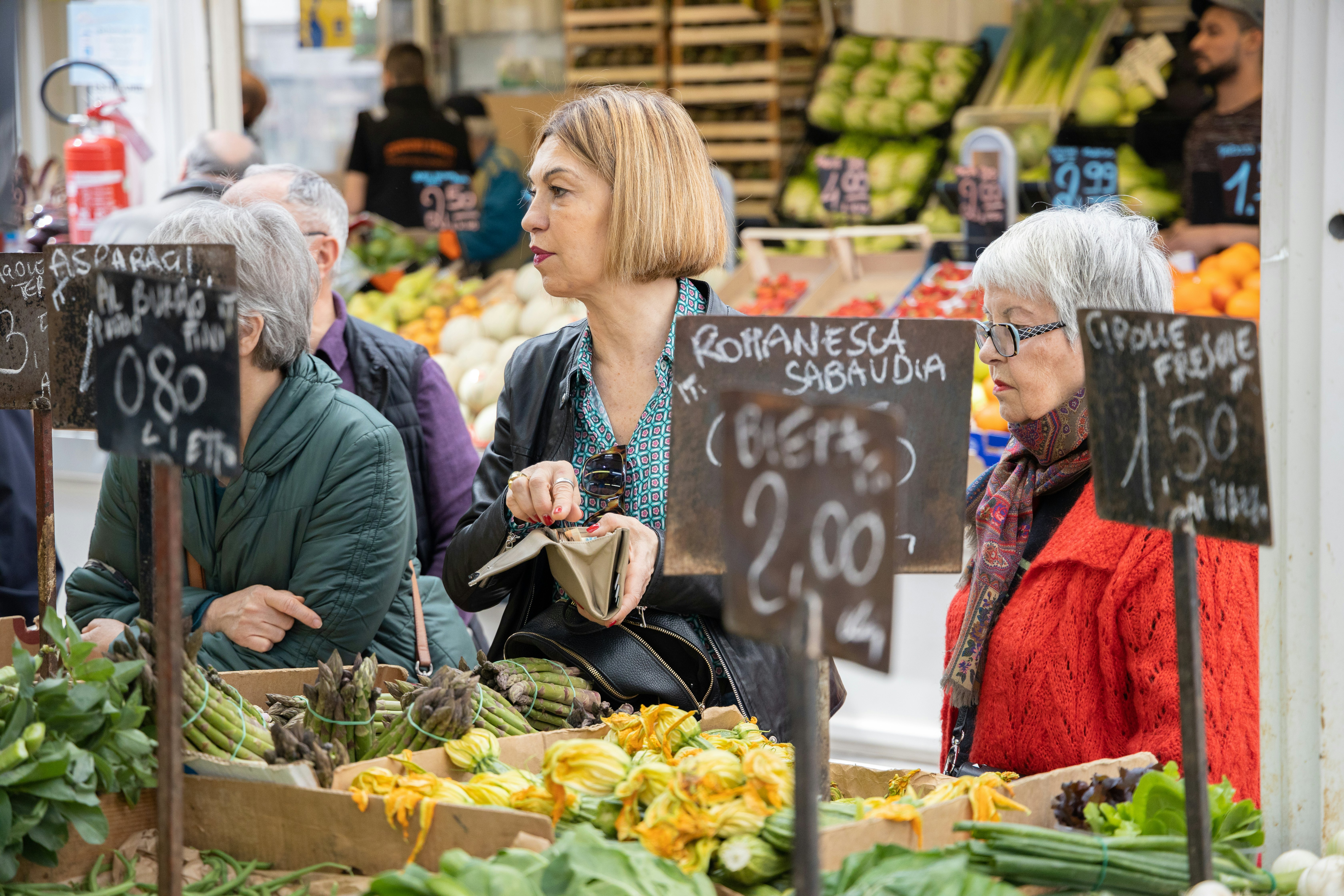 Women queuing up to buy fresh produce in an indoor food market.
