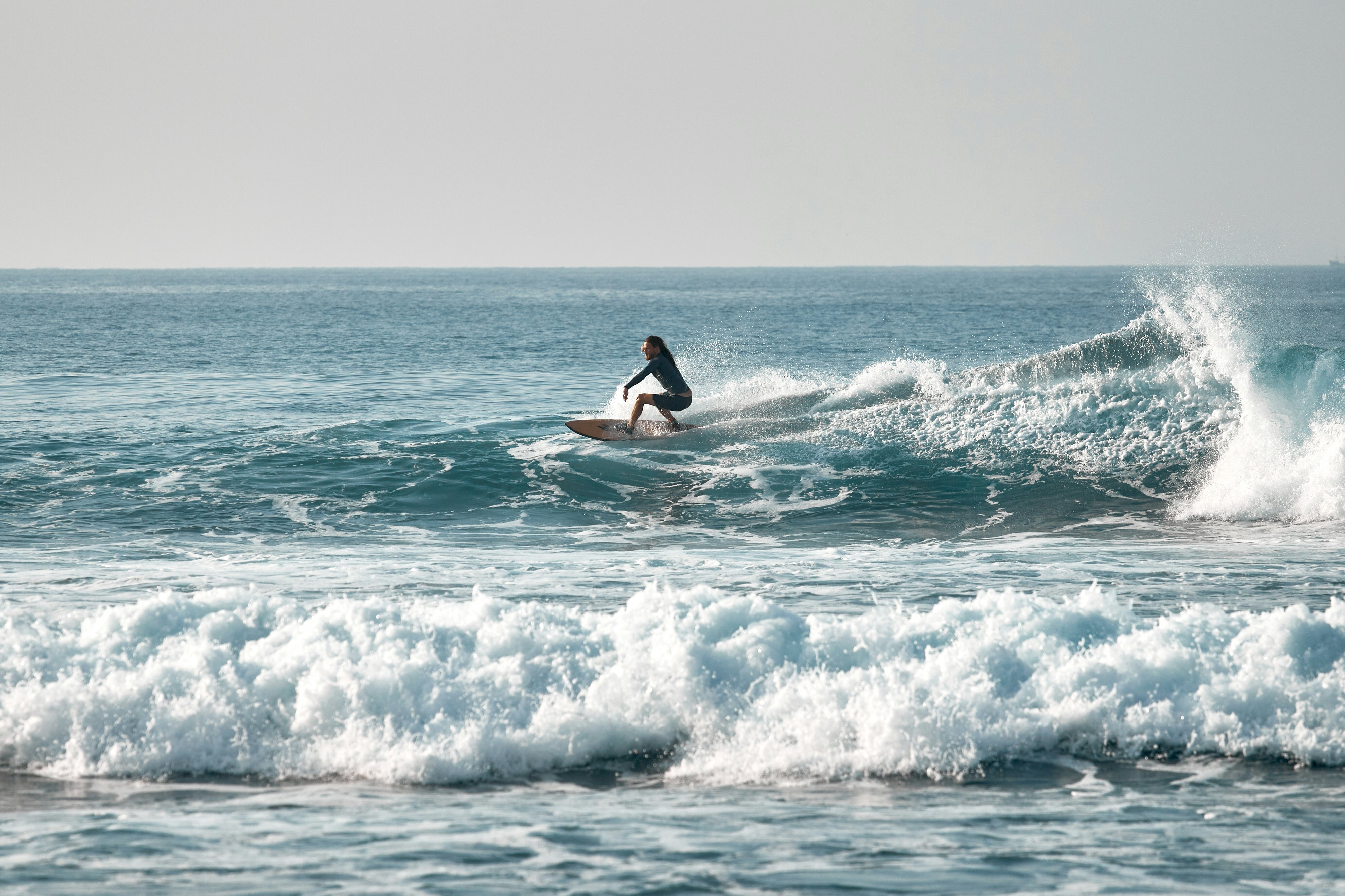 A person rides a wave on a surfboard.