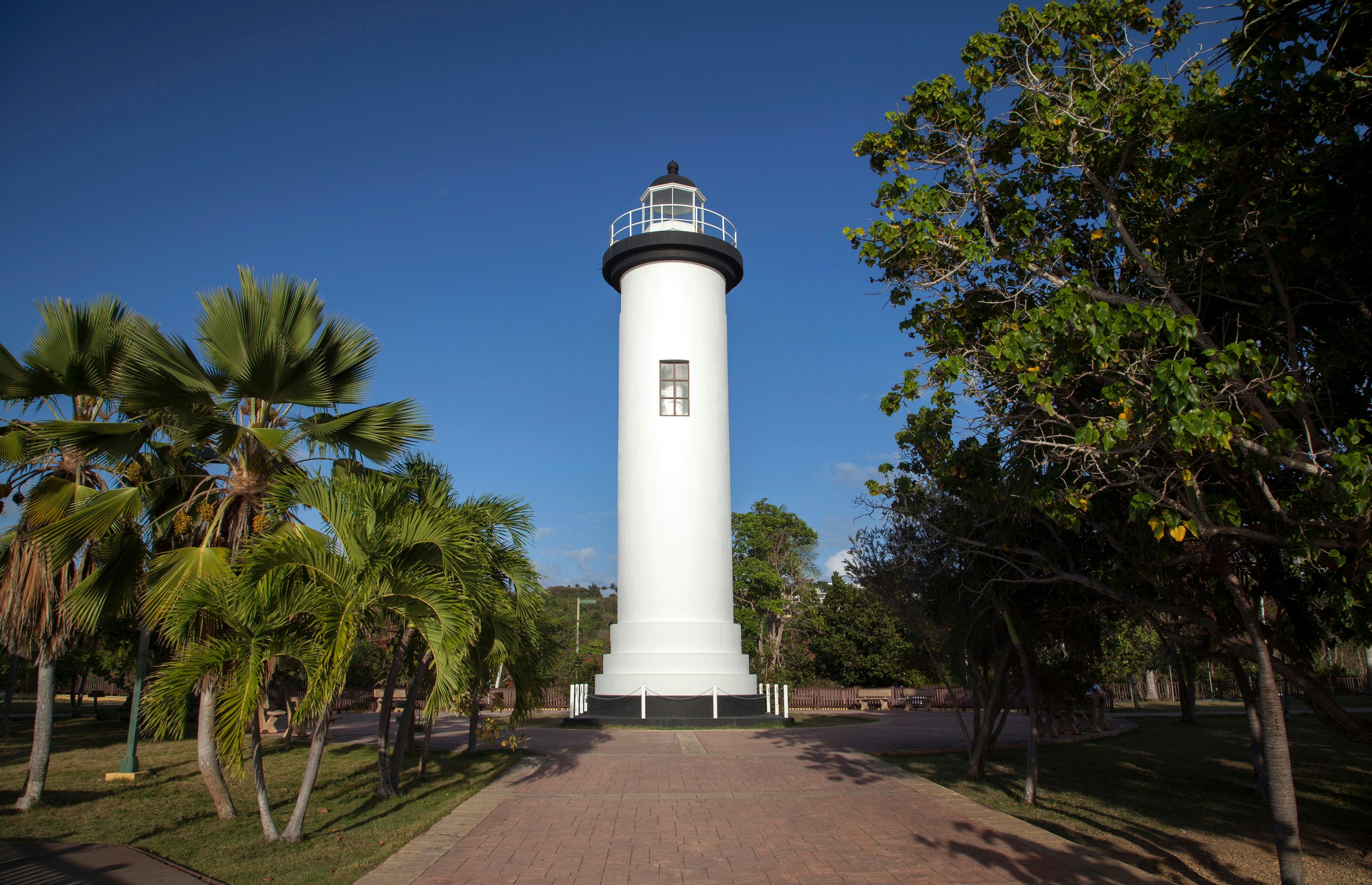 The Punta Higüera Lighthouse under a blue sky with trees all around