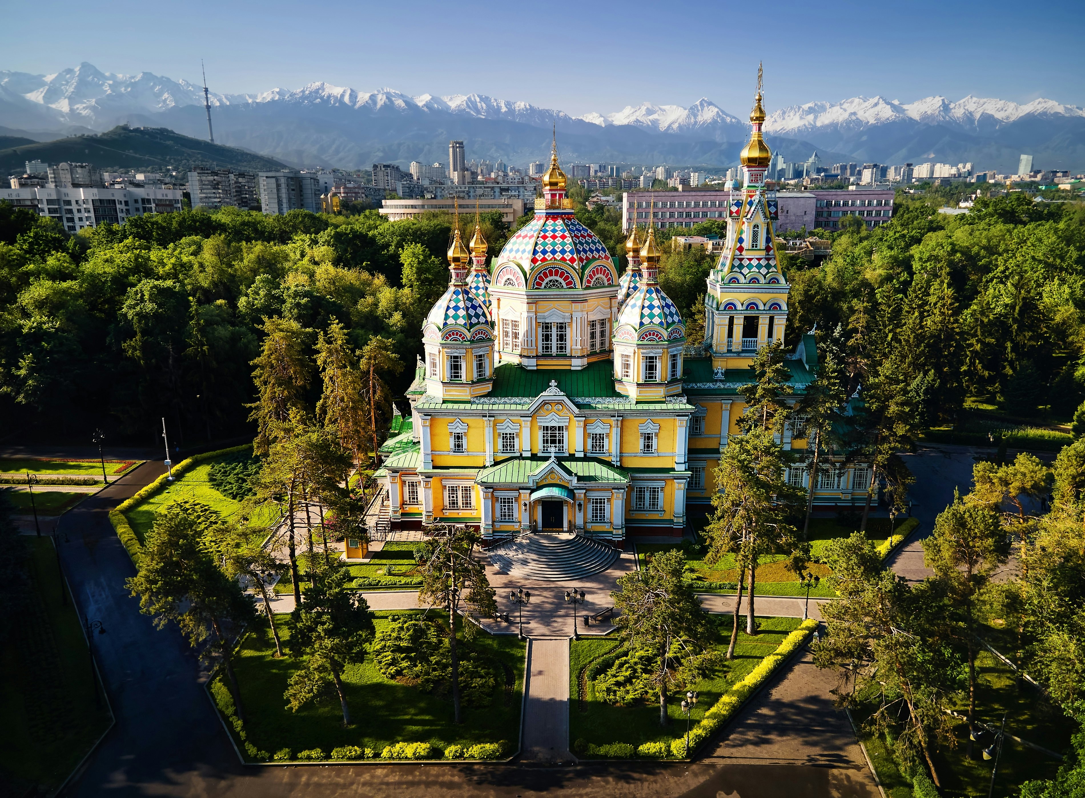 Trees surround the Ascension (Zenkov) Cathedral against a backdrop of mountains in Almaty, Kazakhstan.