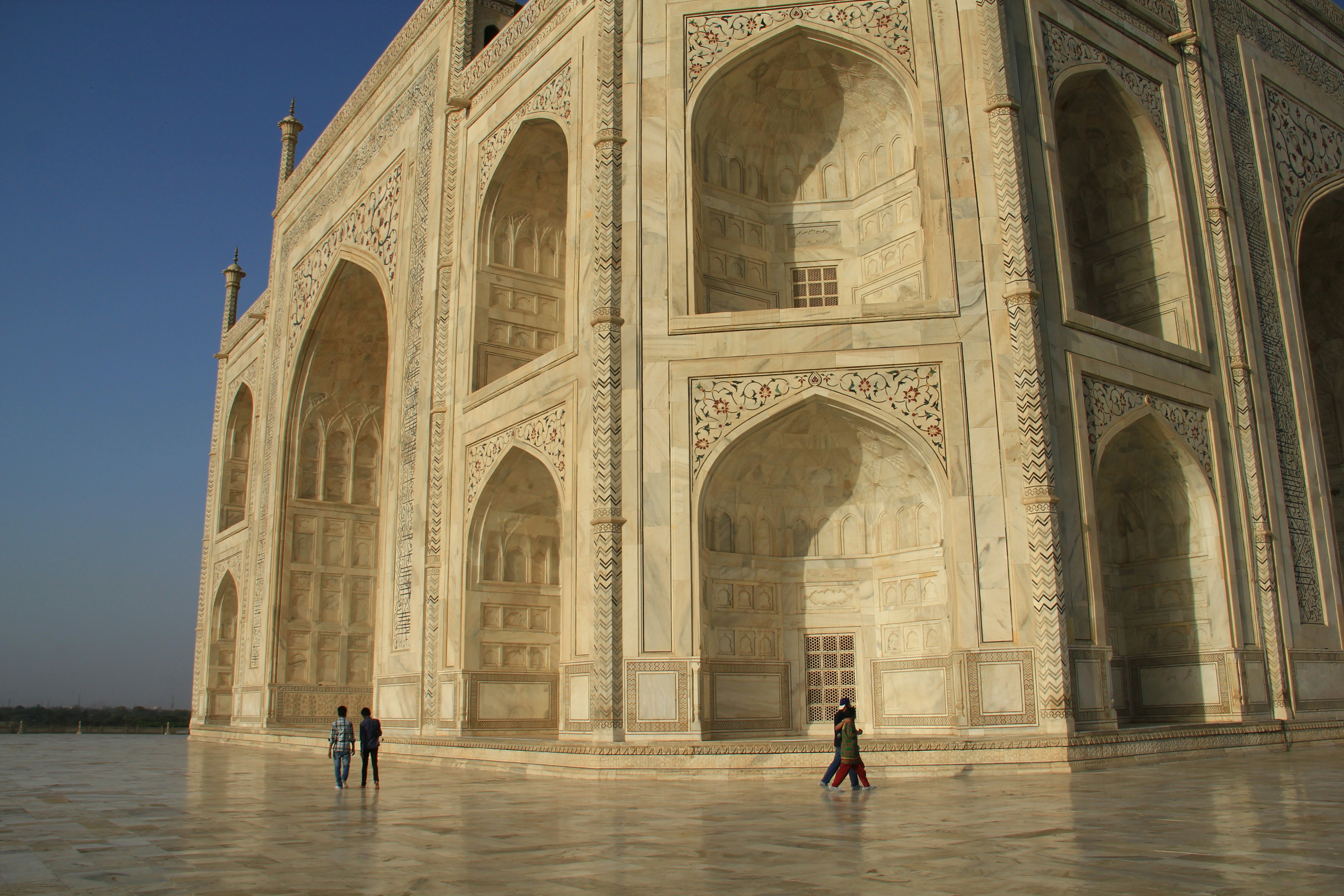 People walk past a huge marble tomb.