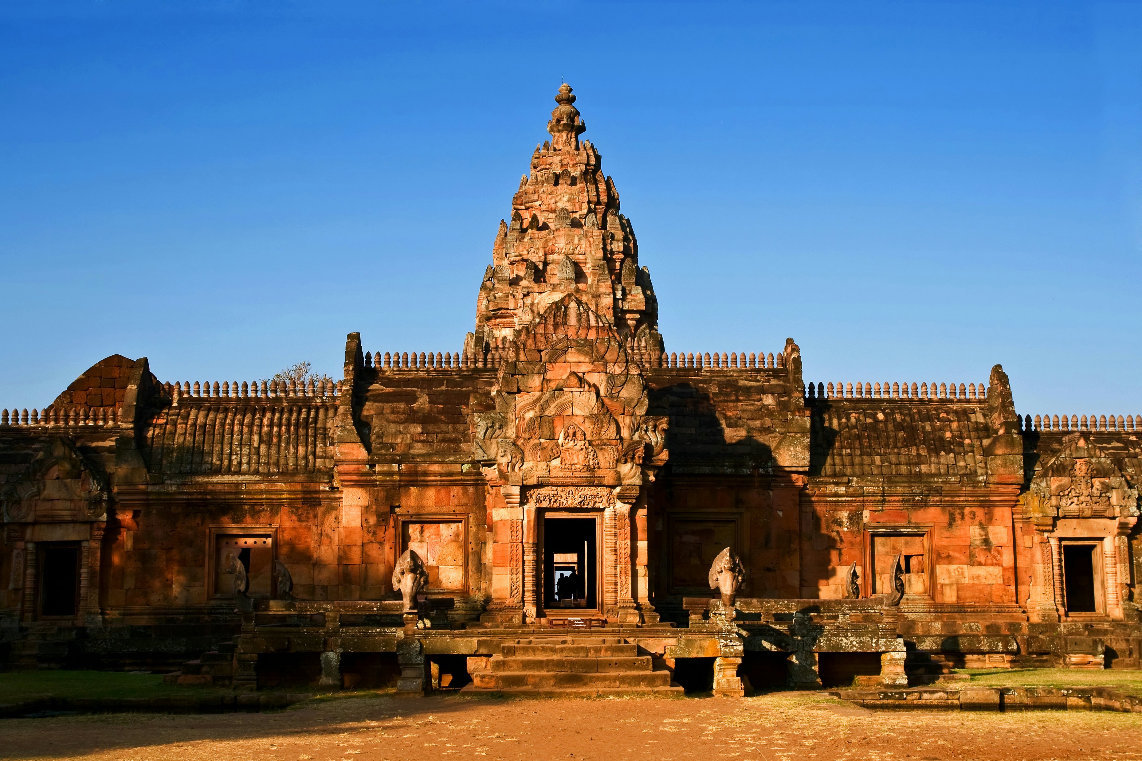 A Khmer temple in Thailand, with a central tower and a few steps leading to a doorway.