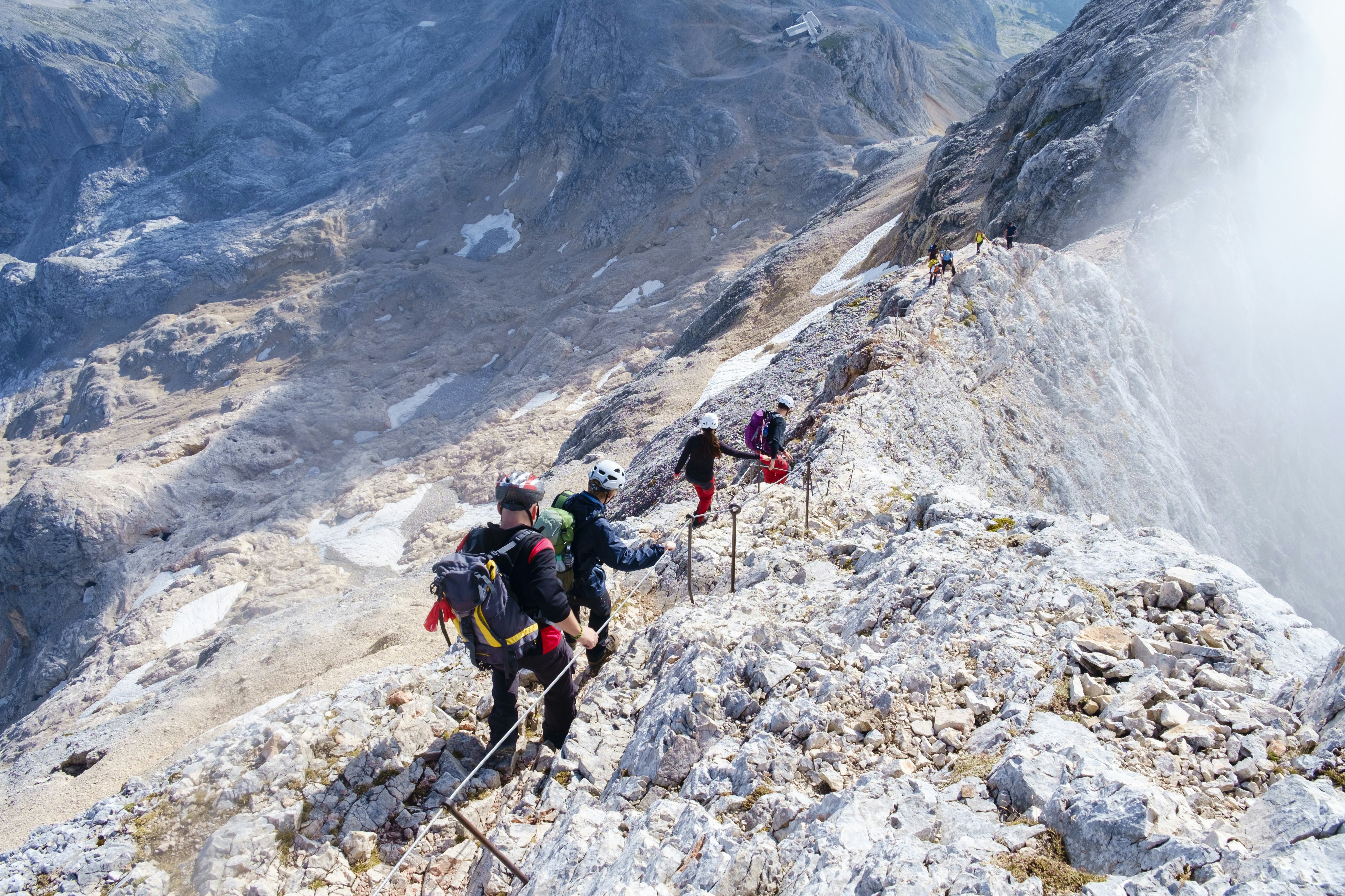 Climbers using a cable to stay stable on a craggy mountain