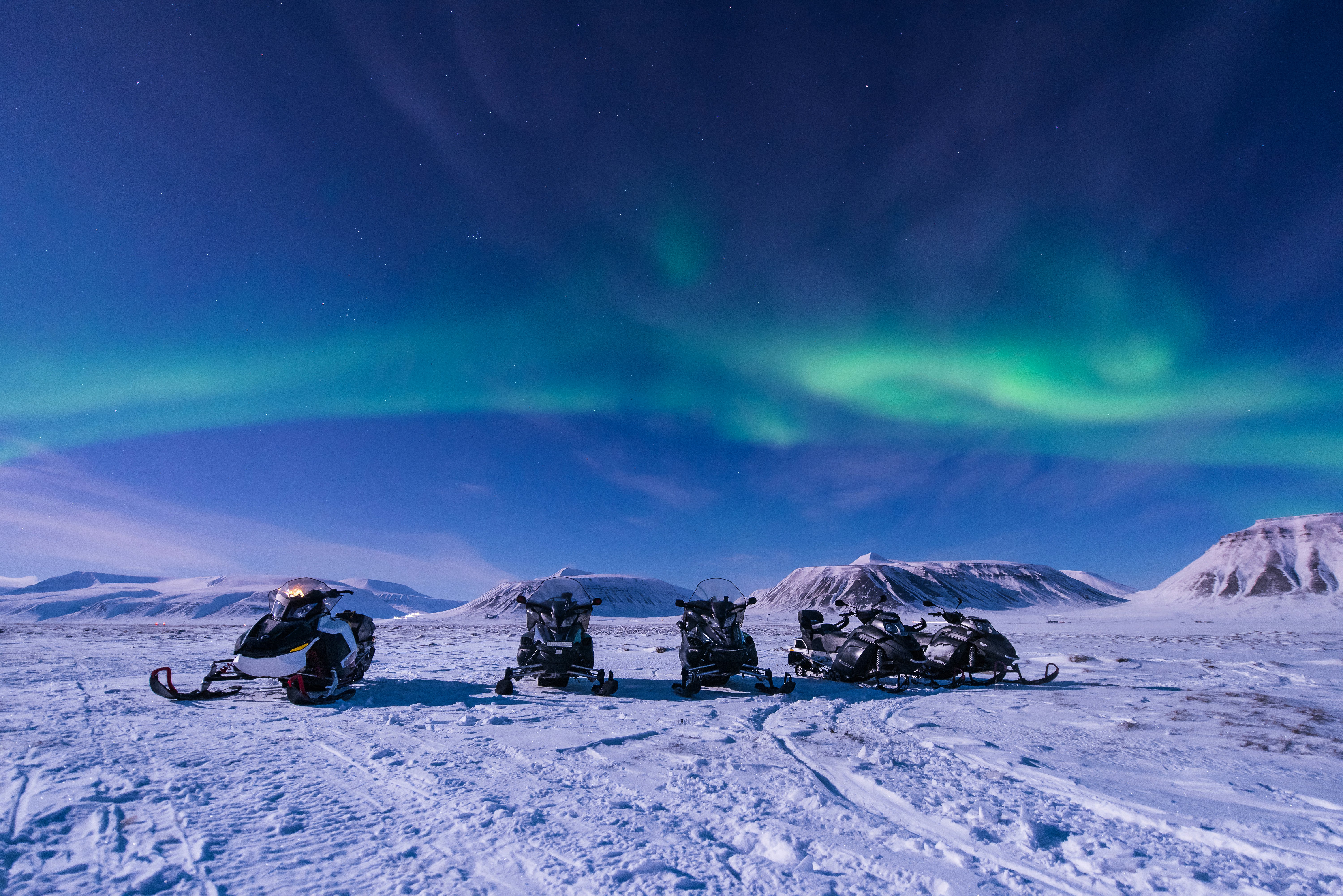 A group of snowmobiles under the Northern Lights.