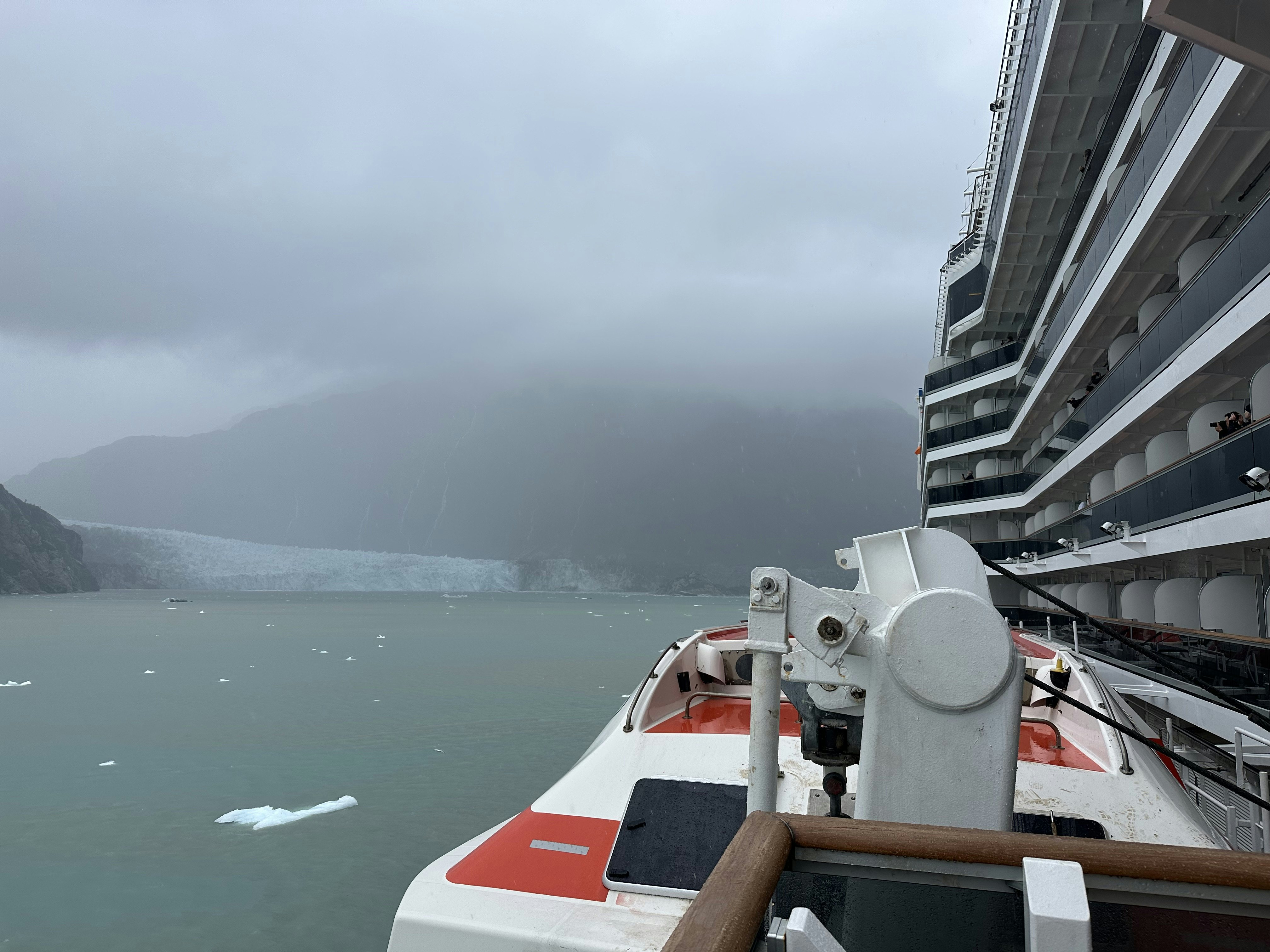 A cruise ship approaching a glacier on an overcast day.