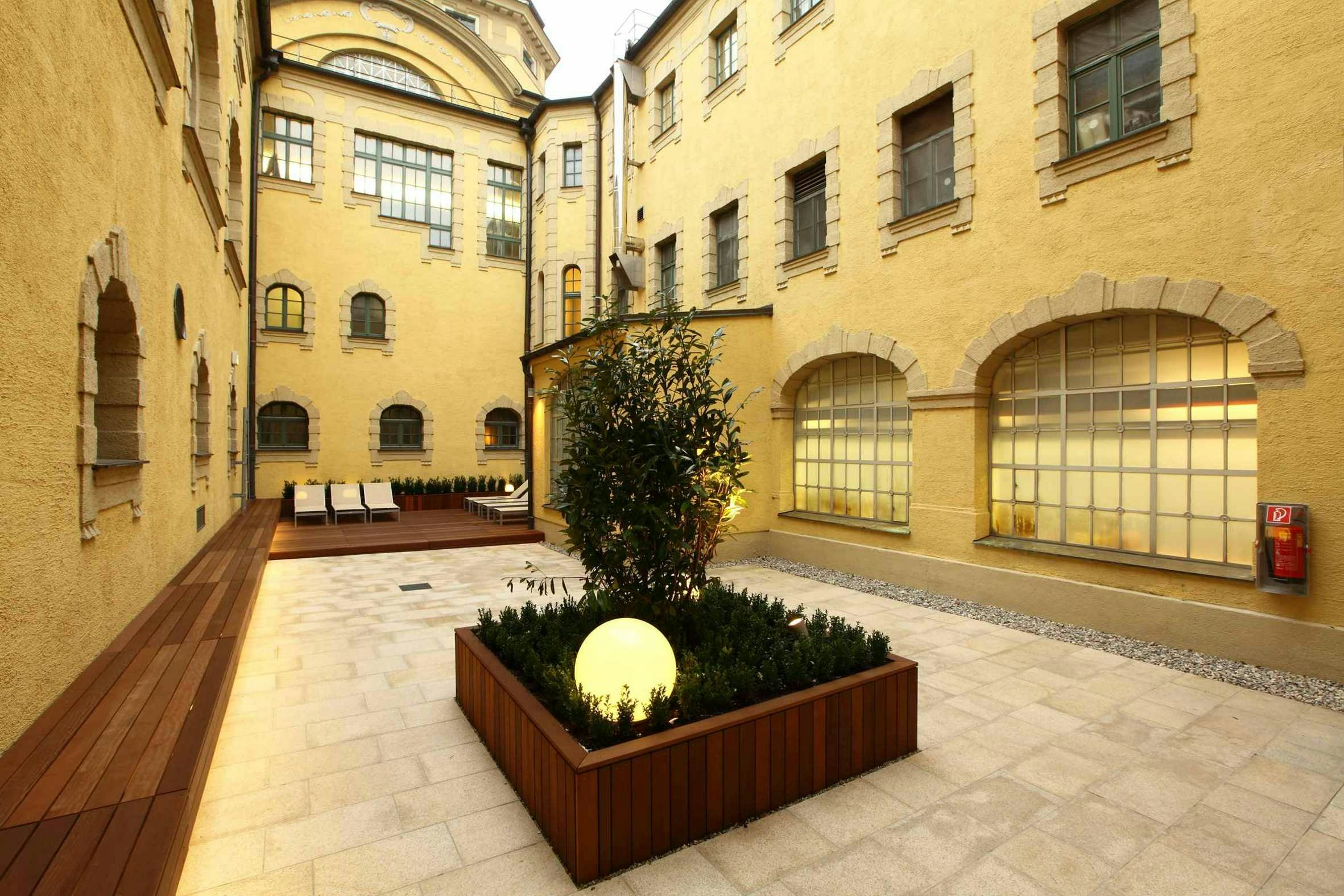A fully enclosed courtyard with a wooden bench running down one side. Loungers are placed on the decking.