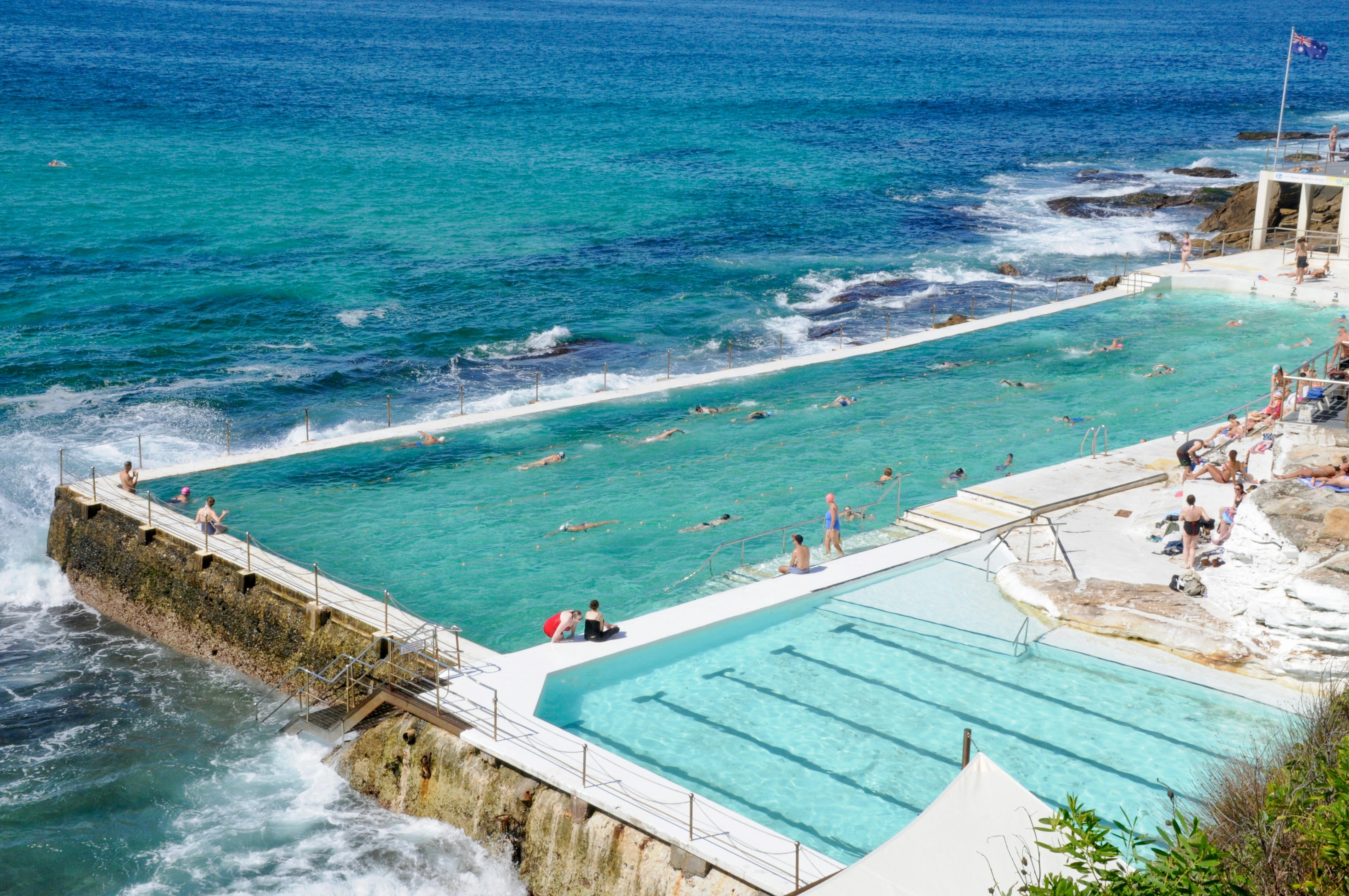 A concrete swimming pool along the seaside on a sunny day.