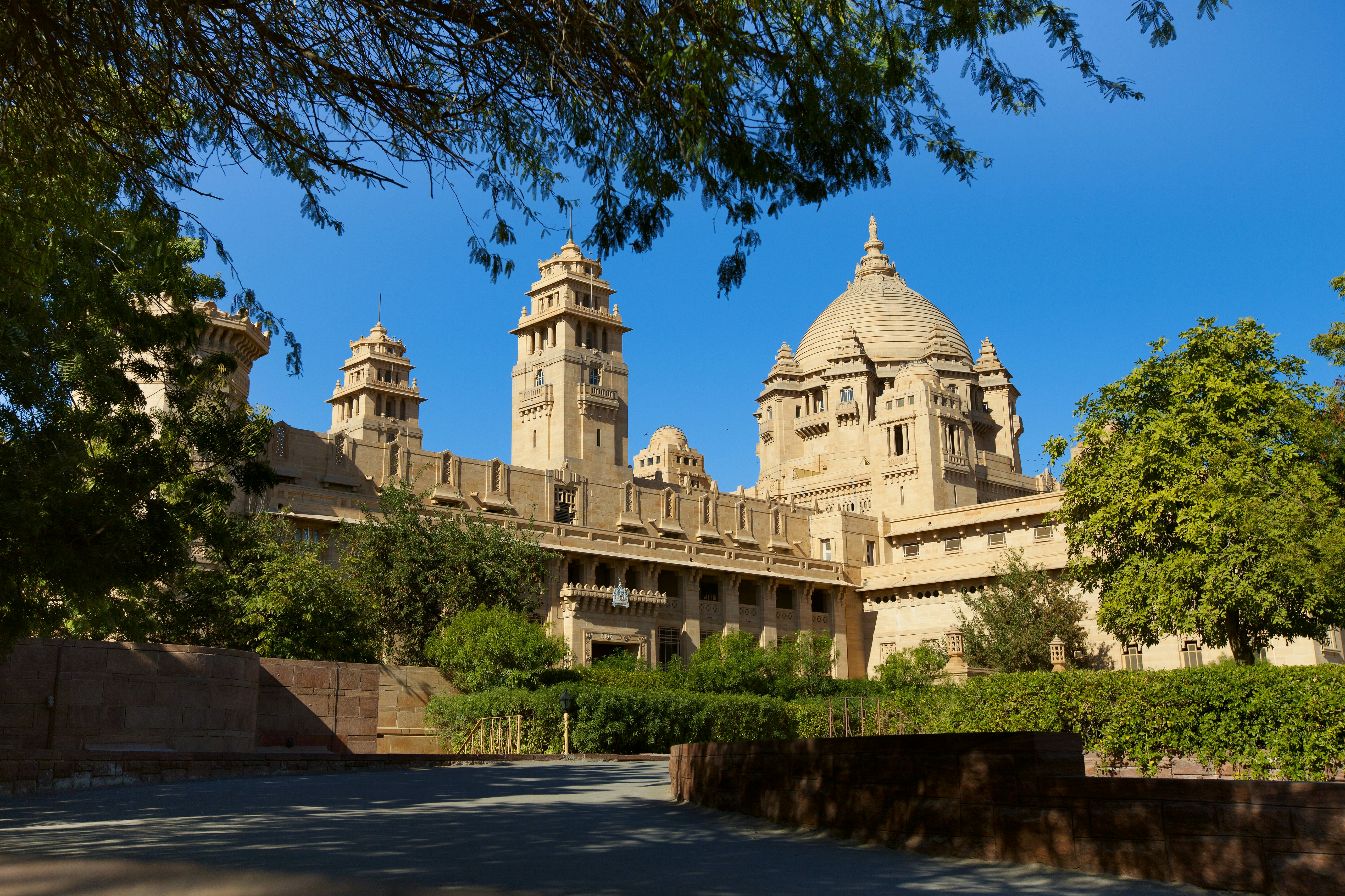 A tan palace with several towers and a dome in India.