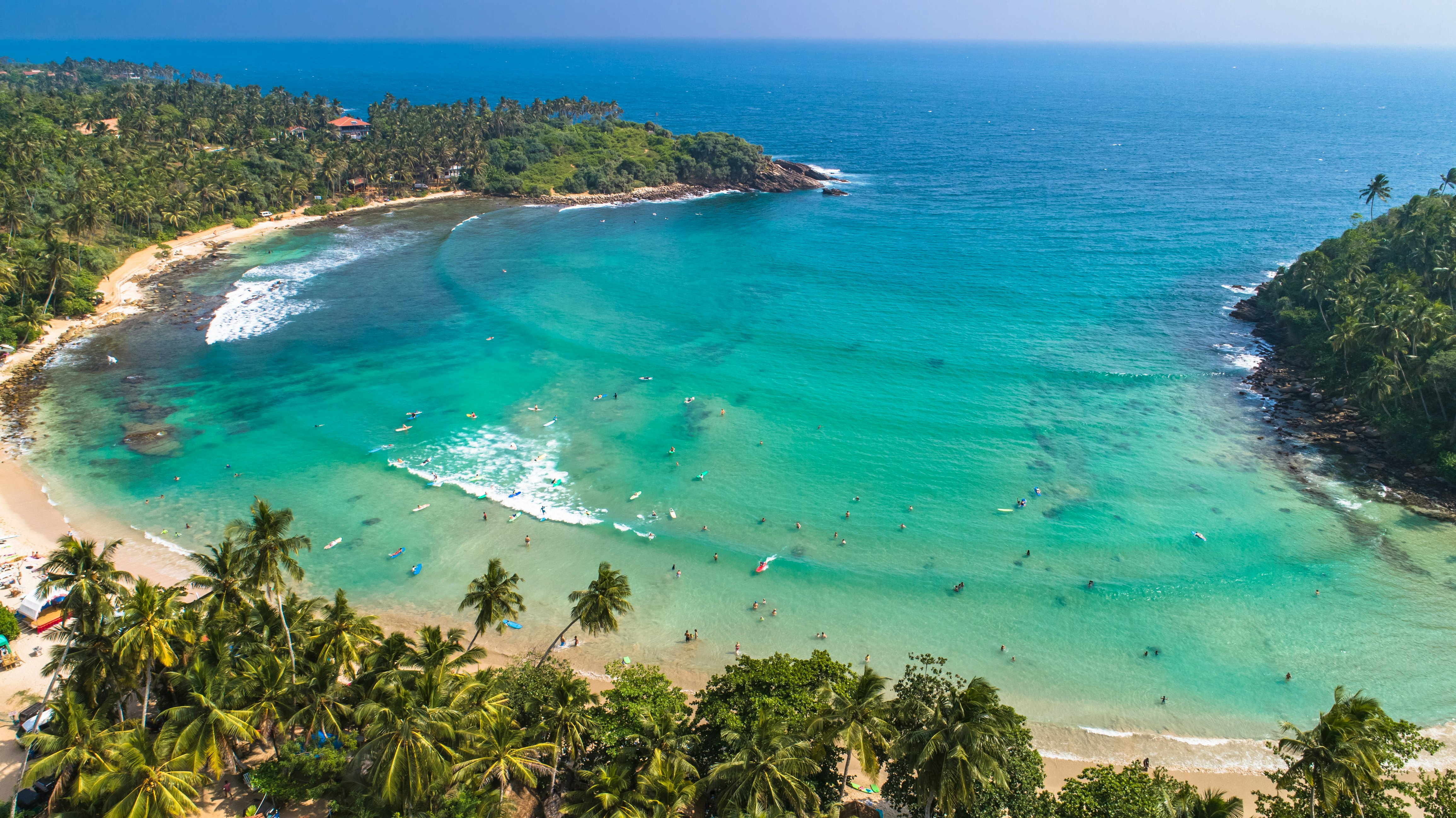 A horseshoe-shaped beach full of surfers.