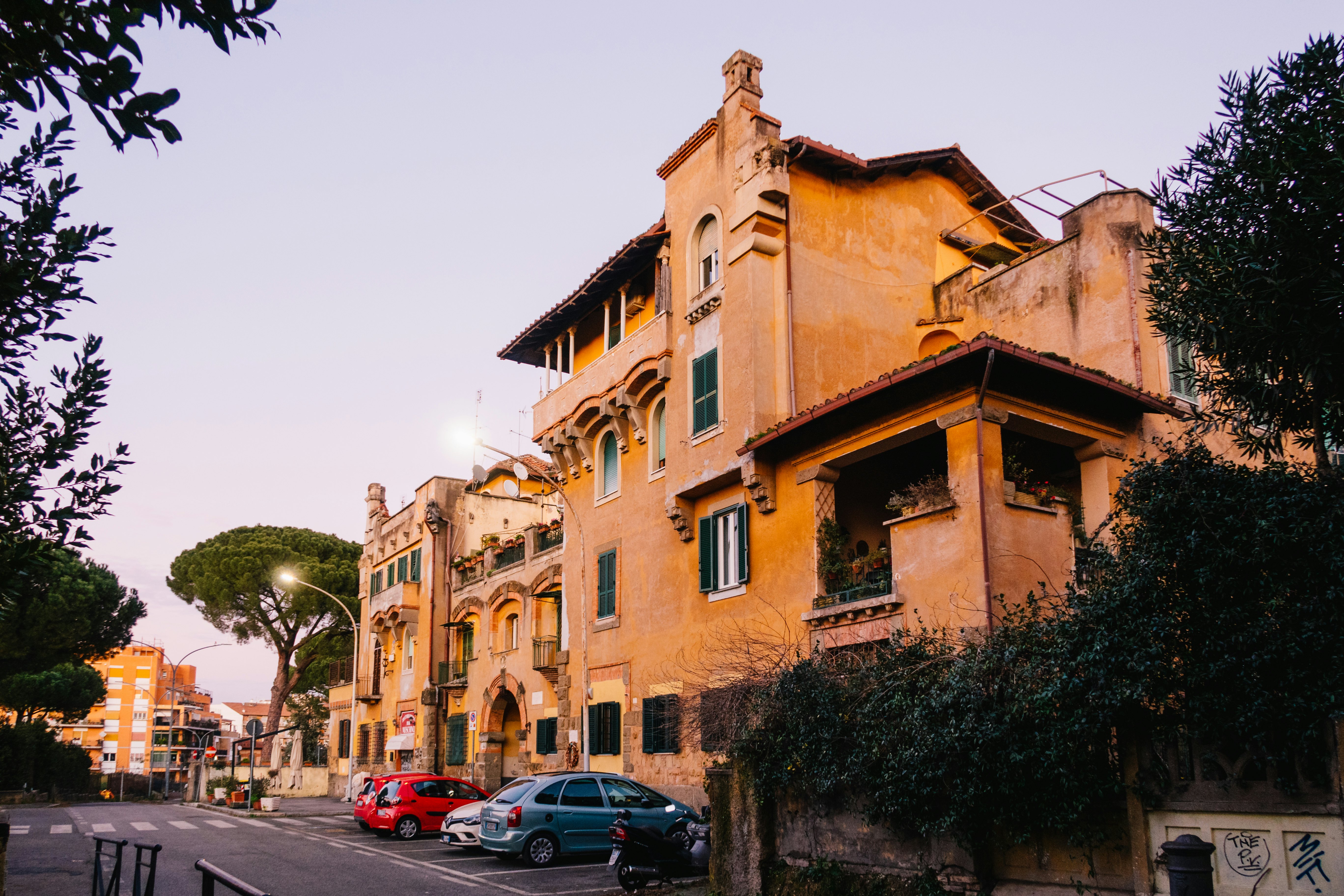 A building with orange facade facing a tree and cars parked outside
