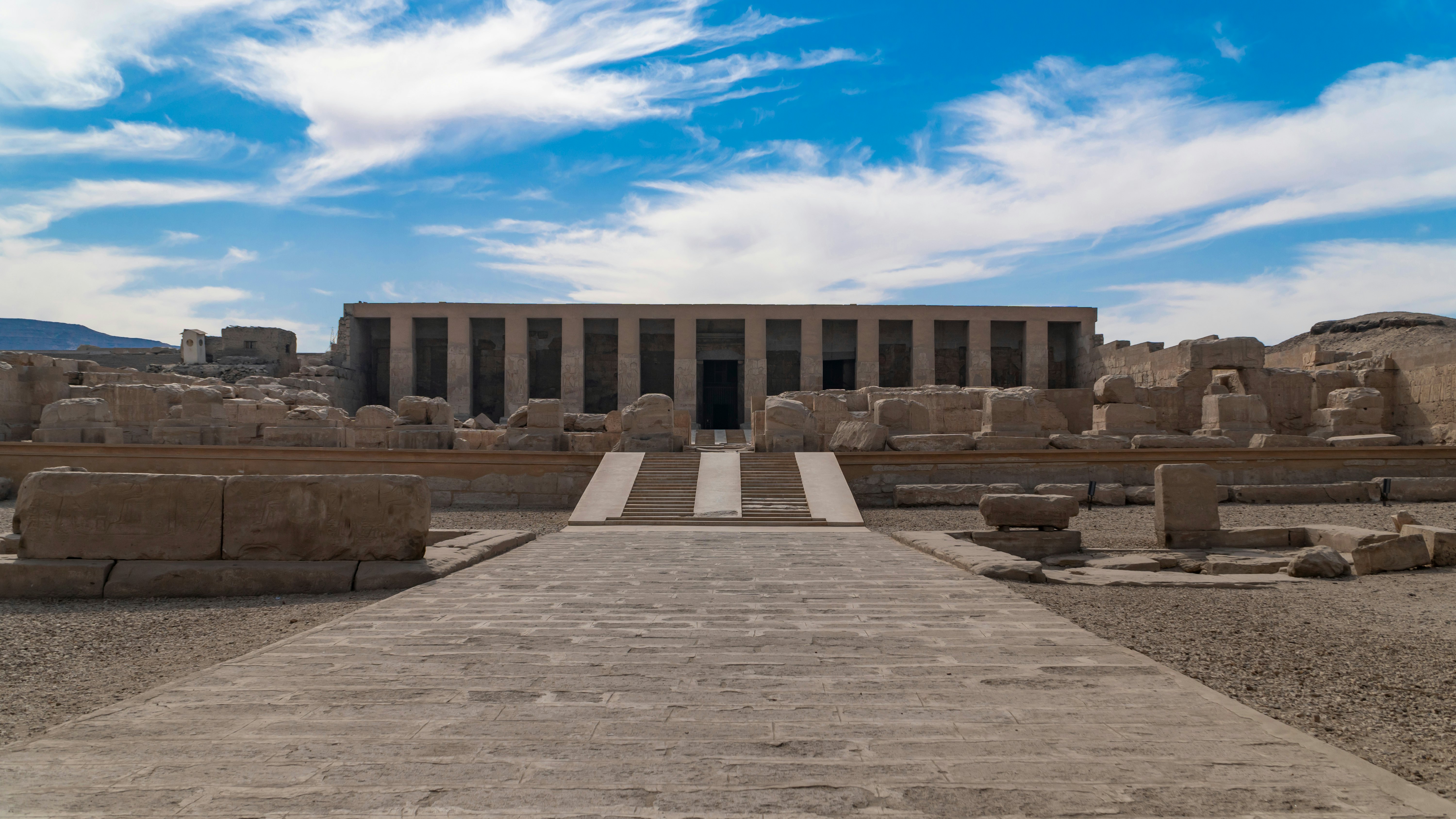 A temple set back against a blue sky with white clouds