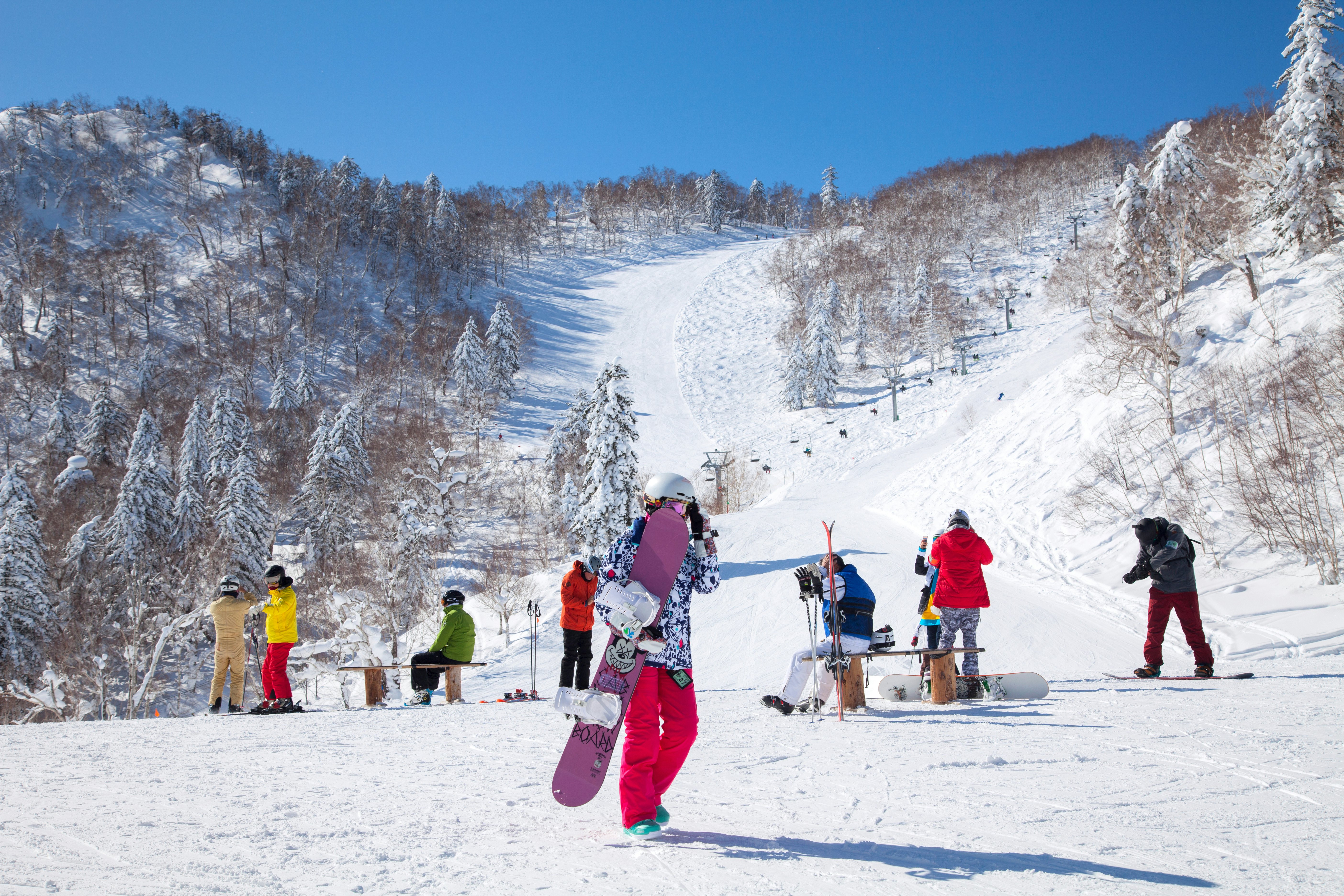 Skiers and snowboarders surrounded by snowy mountain slopes.