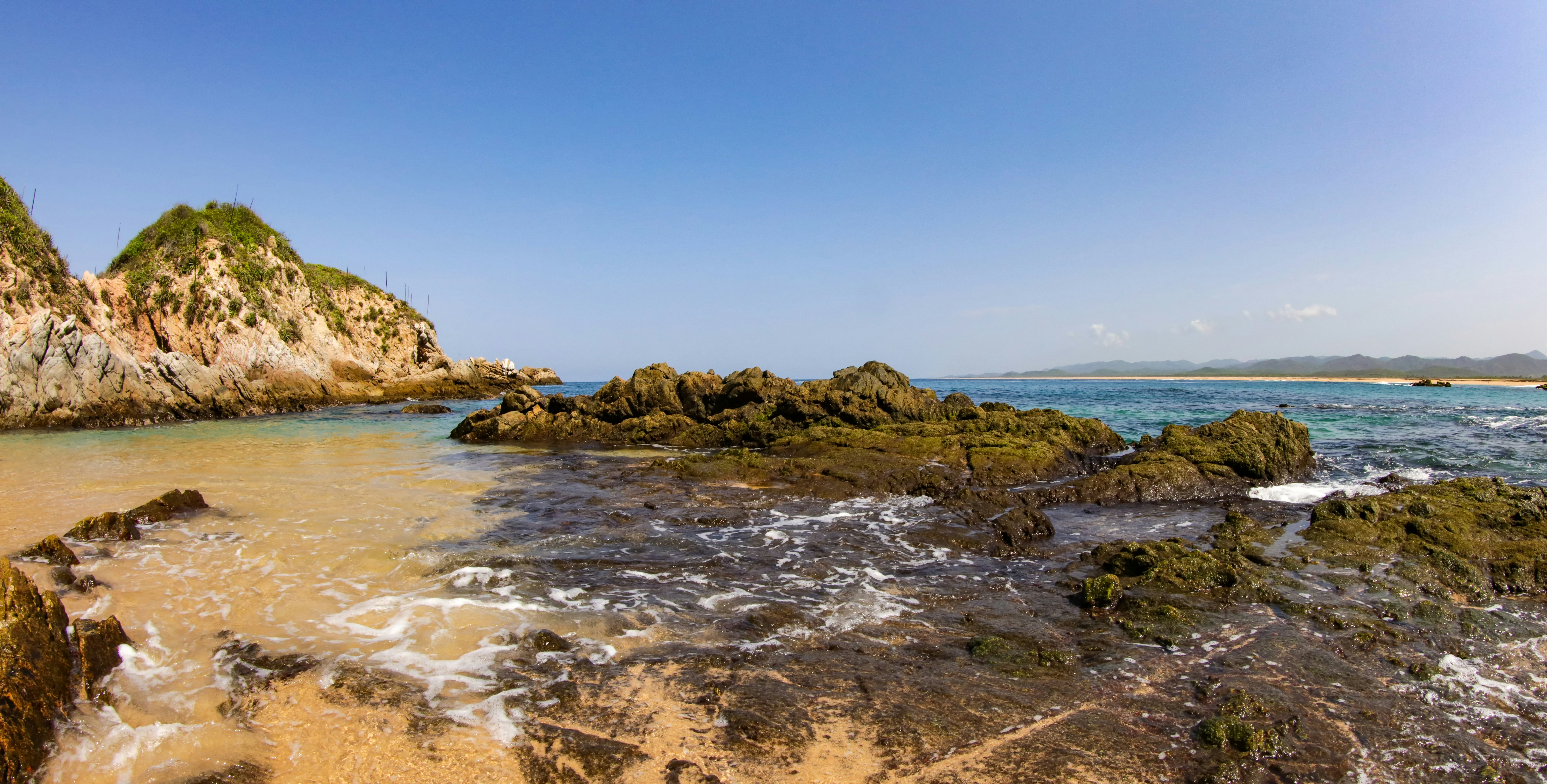 The beautiful rock formations on Mayto Beach in Jalisco, Mexico. Covered in clear ocean water. Bright blue sky with no clouds.