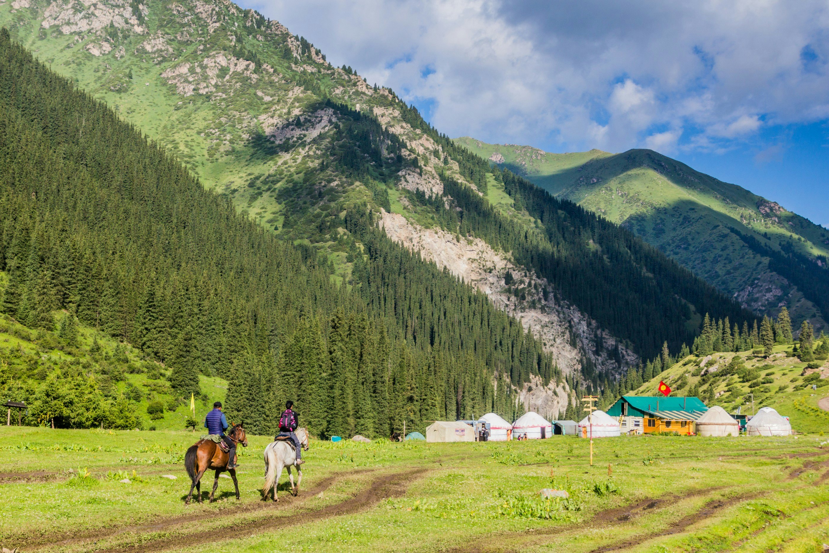 Villagers on horseback near a yurt camp in Altyn Arashan, Kyrgyzstan.