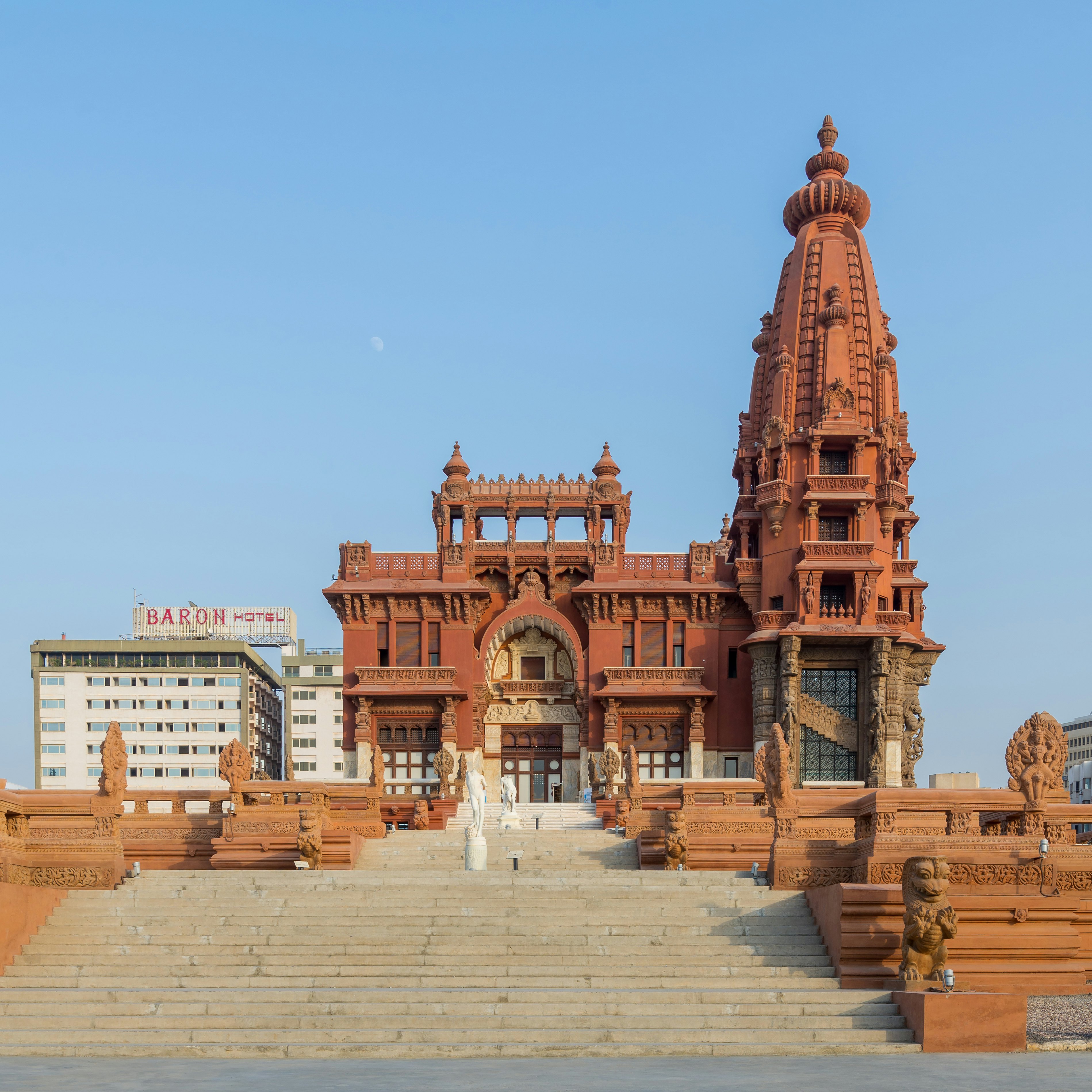Sand colored stairs and large red brick minaret of the Baron Empain Palace in Cairo, Egypt.
