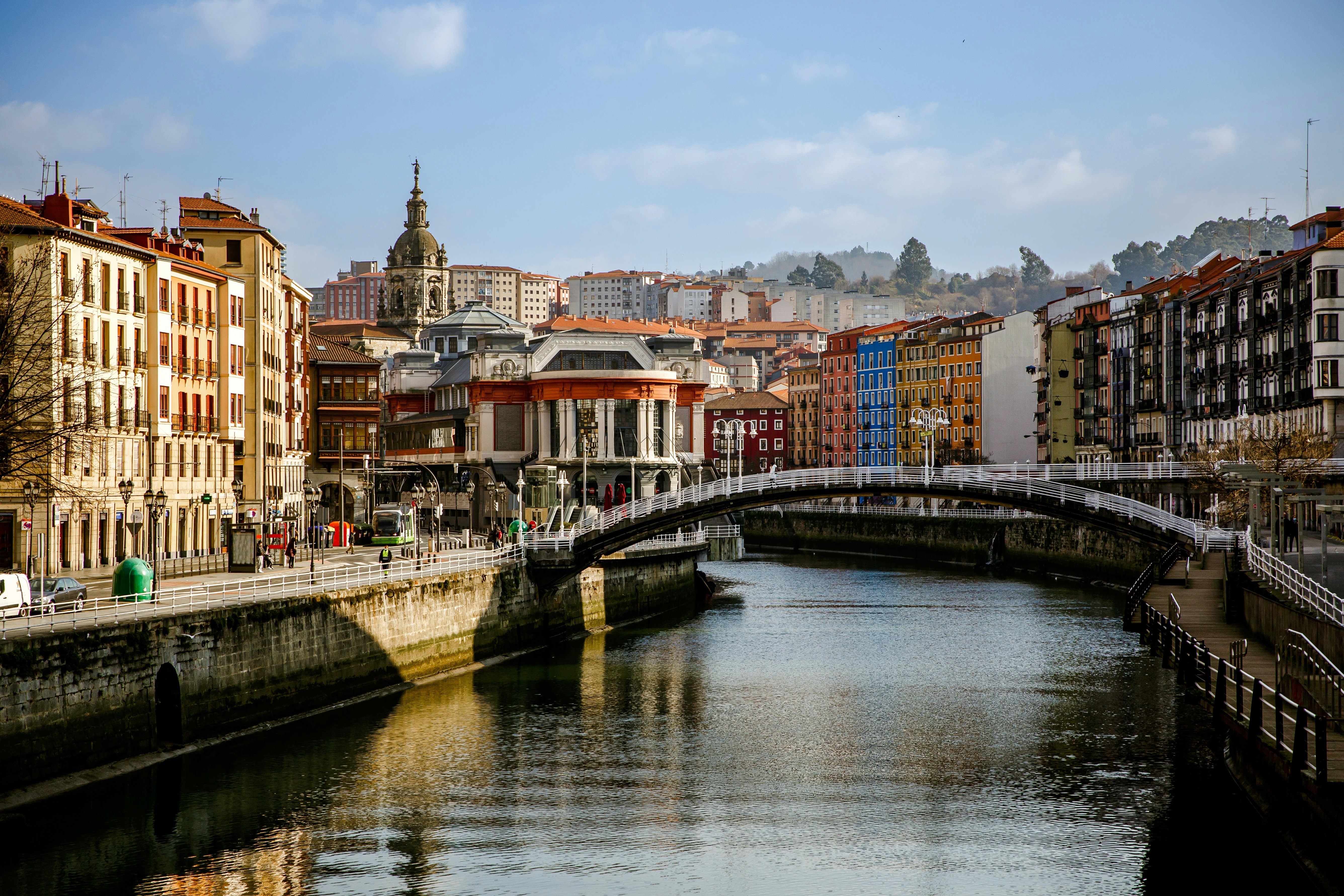 Street along a canal with a bridge going over it.