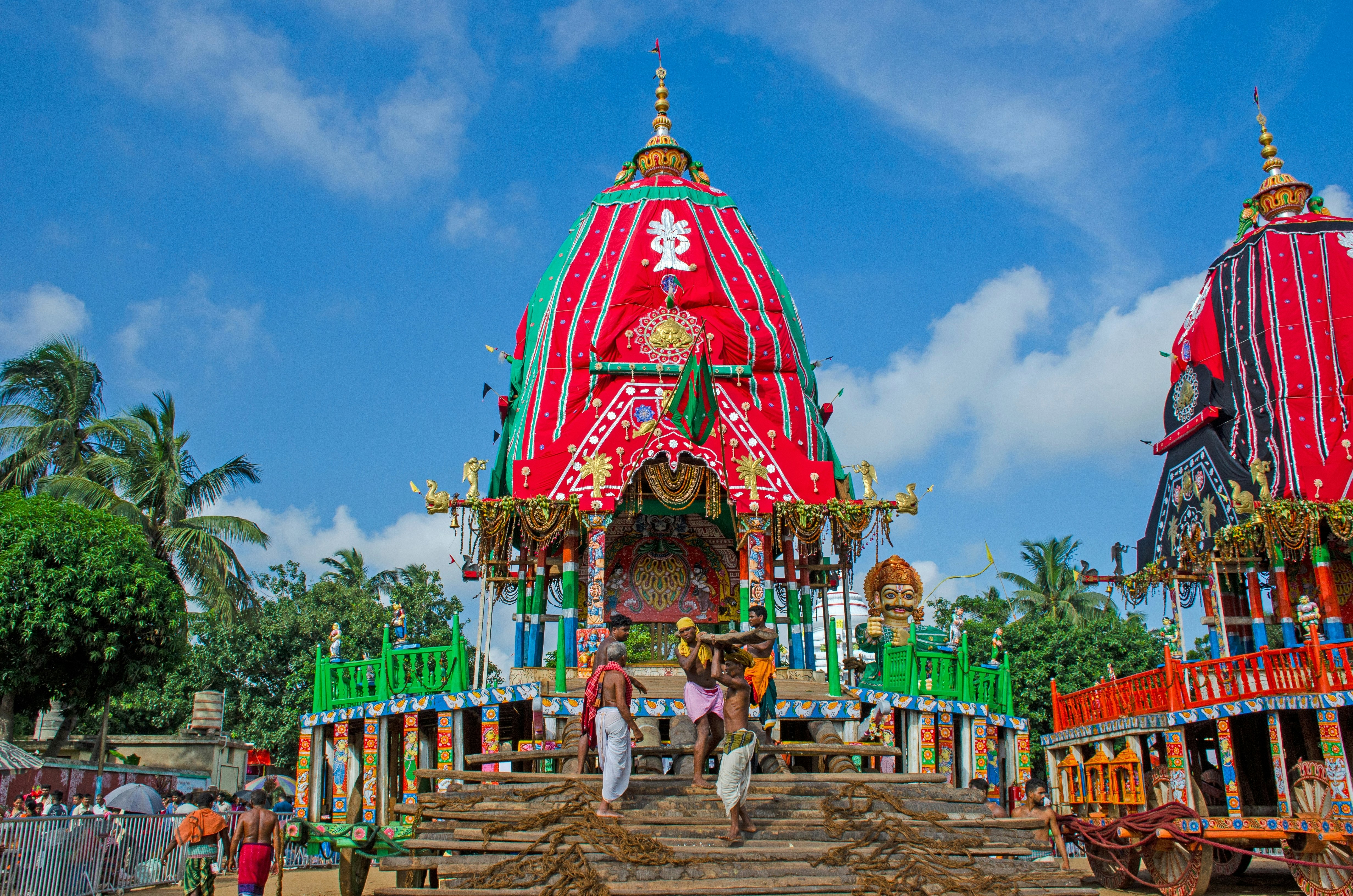People stand on steps in front of an elaborately decorated temple tower.