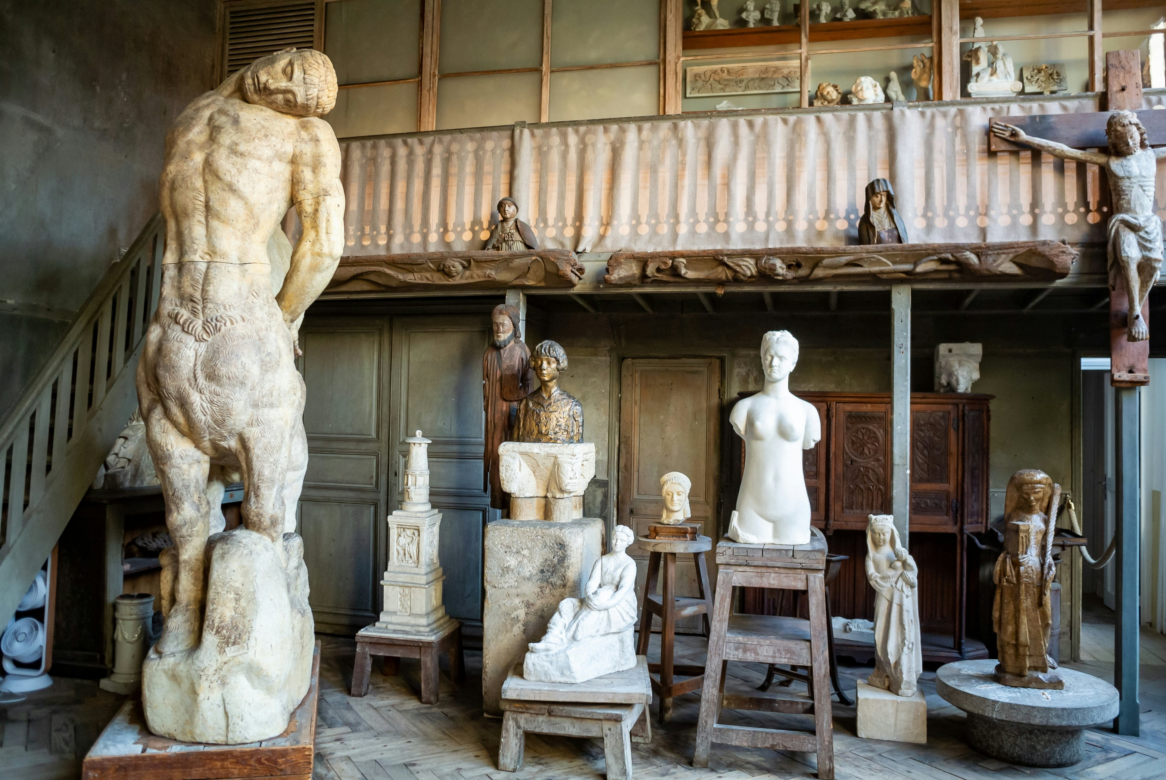 Figurative marble sculptures and wooden carvings in an artist's studio.