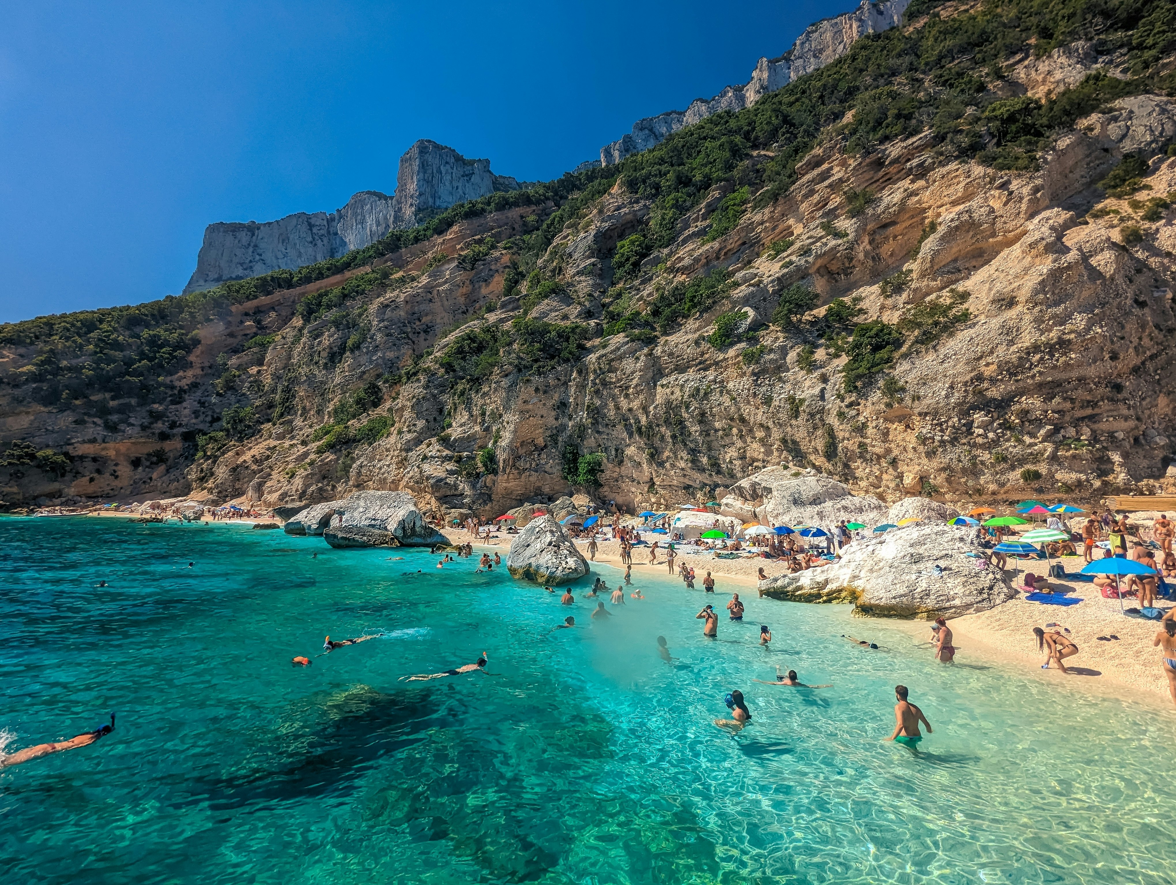 People enjoy the beach at Cala Mariolu, on the east coast of Sardinia, Italy.