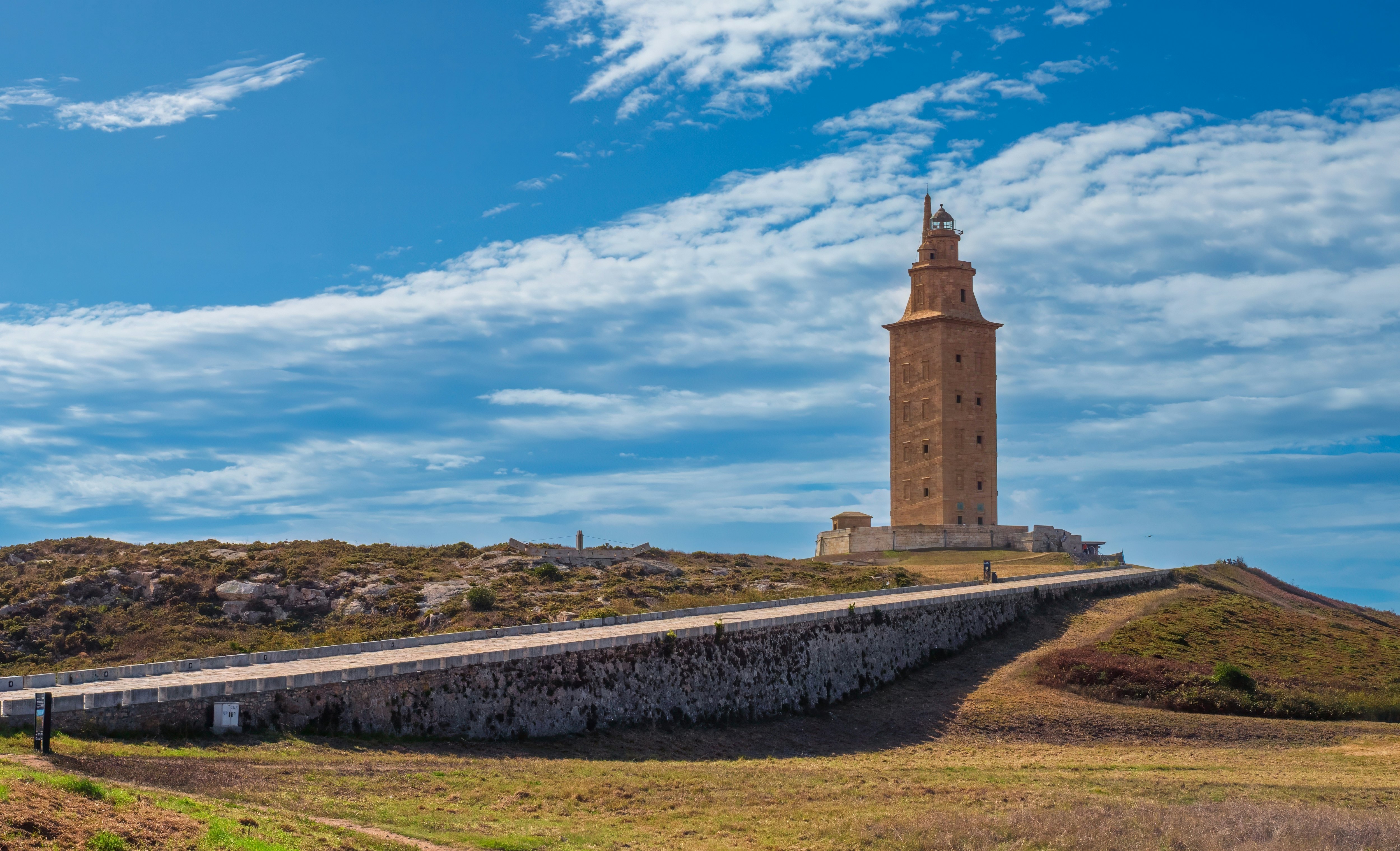 An ancient Roman lighthouse in A Coruña, with a stone walkway nearby.