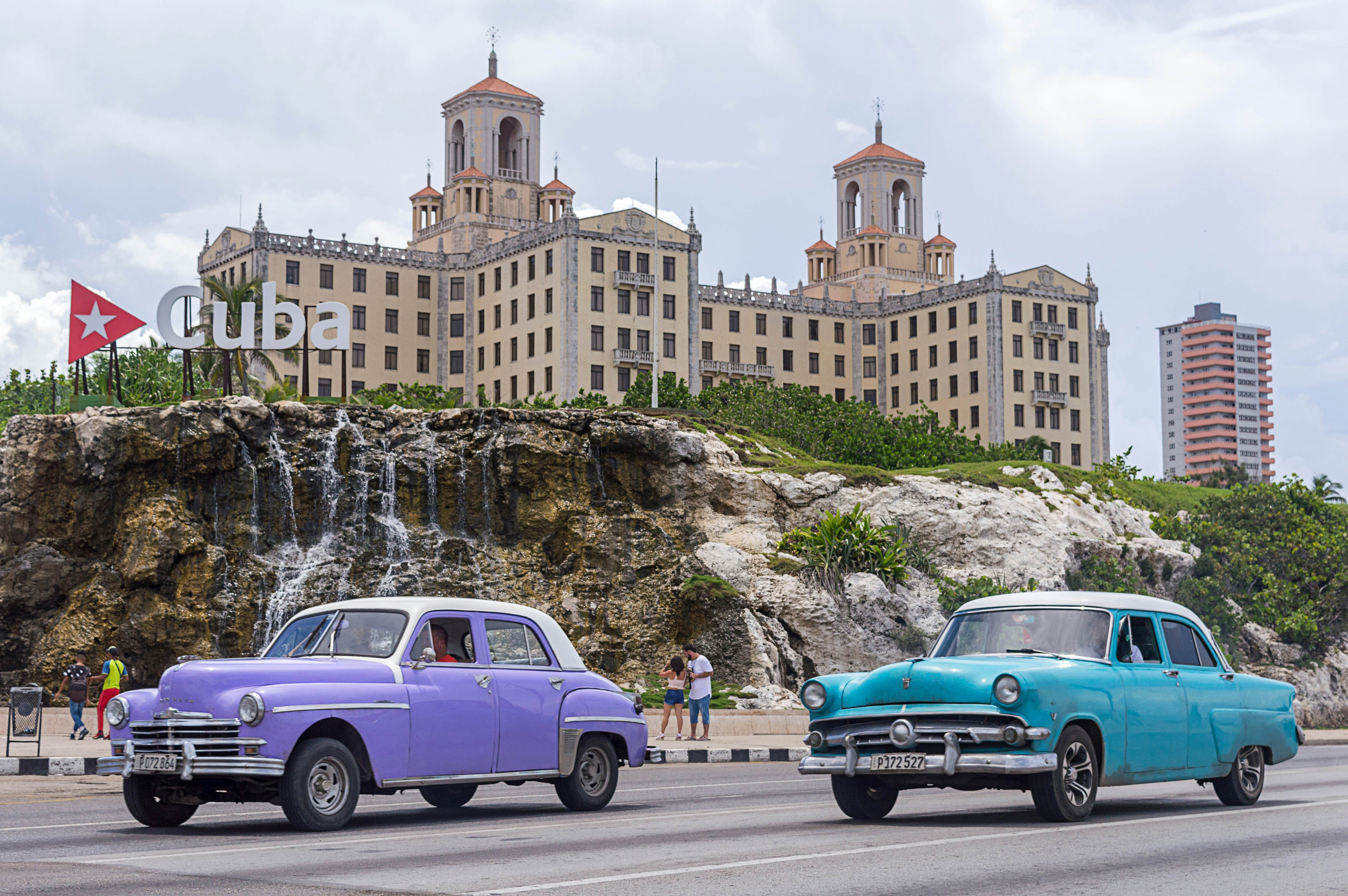 Two classic cars driving along Malecon Avenue, and in the background you can see the National Hotel of Cuba. Havana - Cuba. date 5 November 2018, License Type: media, Download Time: 2025-11-27T19:39:51.000Z, User: bhealy950, Editorial: true, purchase_order: 65050 - Digital Destinations and Articles, job: Lonely Planet Online Editorial, client: Accommodations in Cuba, other: Brian Healy