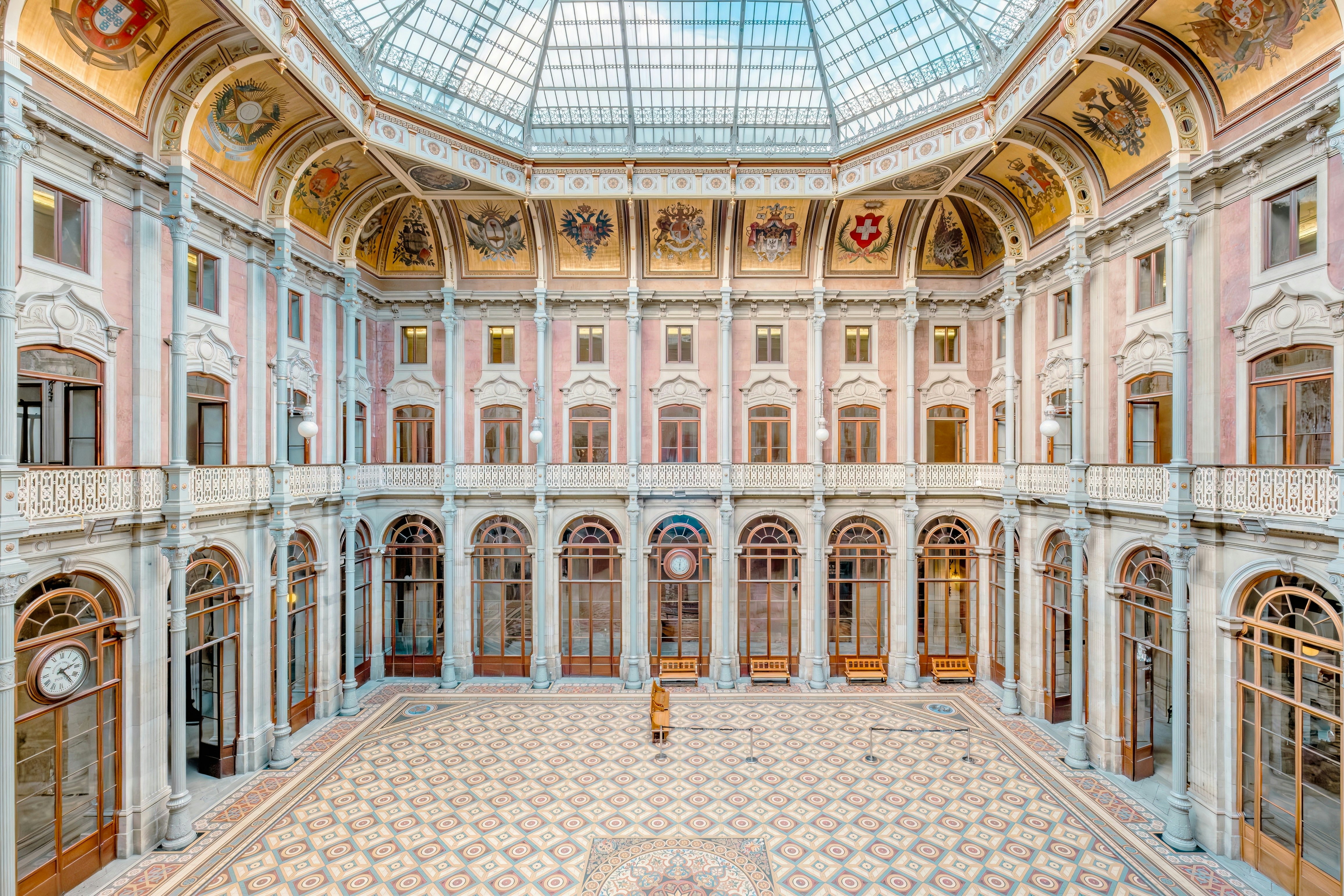 The empty floor of a vast stock exchange, with intricate tiling, golden motifs on the ceiling and a large glass dome.