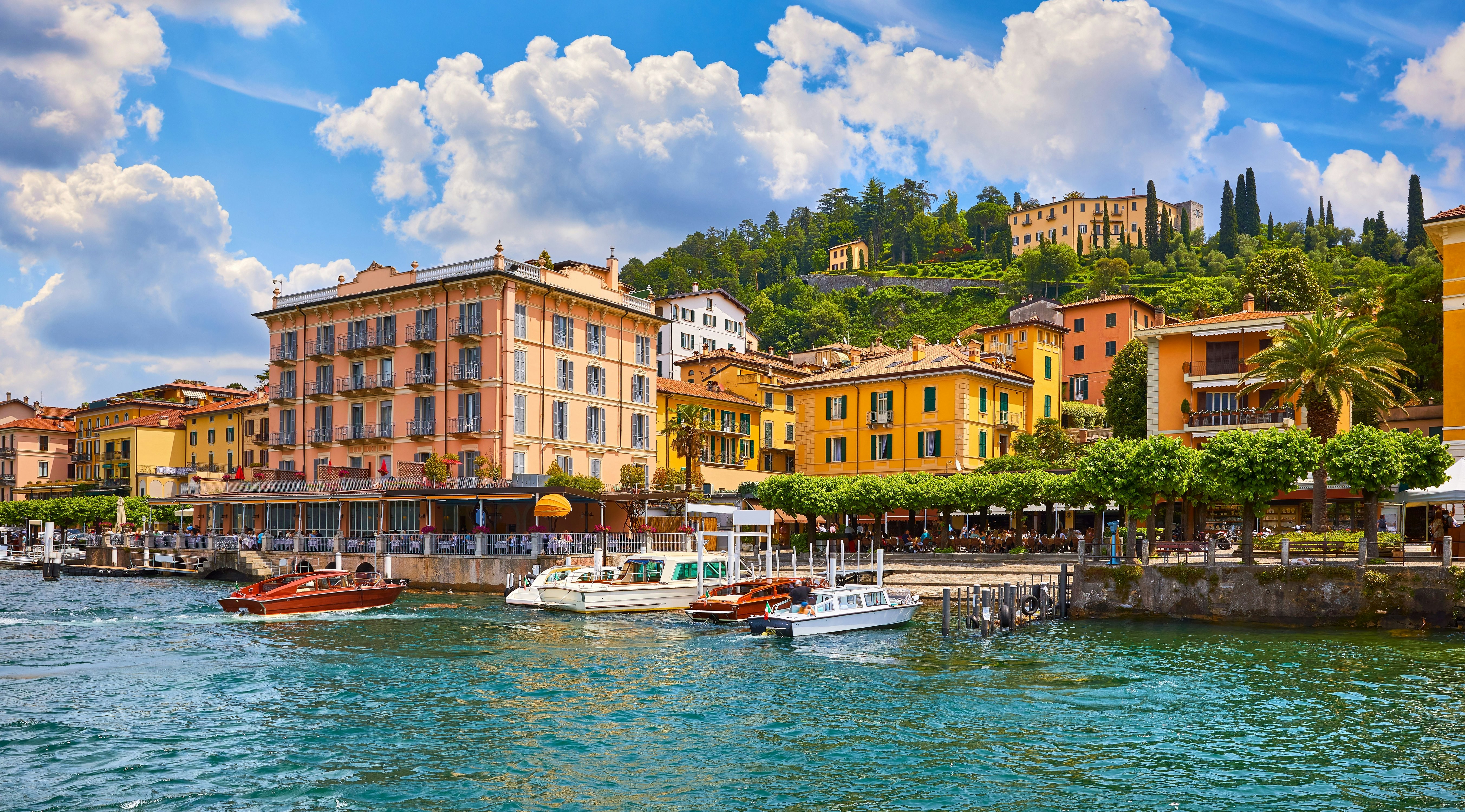Famous Italian village of Bellagio with ochre and peach-colored buildings overlooking a harbor with boats