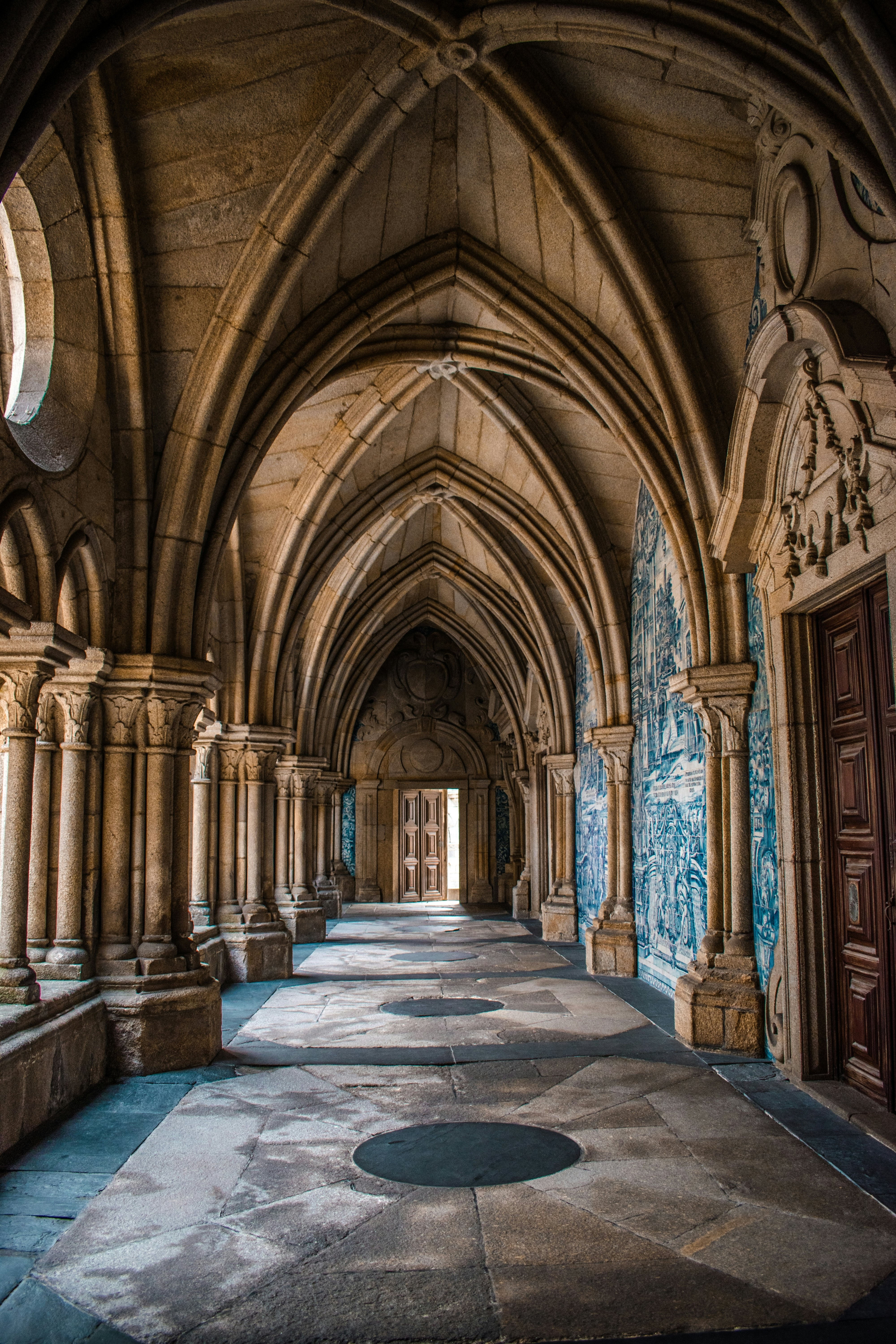 Cloisters within a cathdral. The walls are decorated with blue and white tiles.