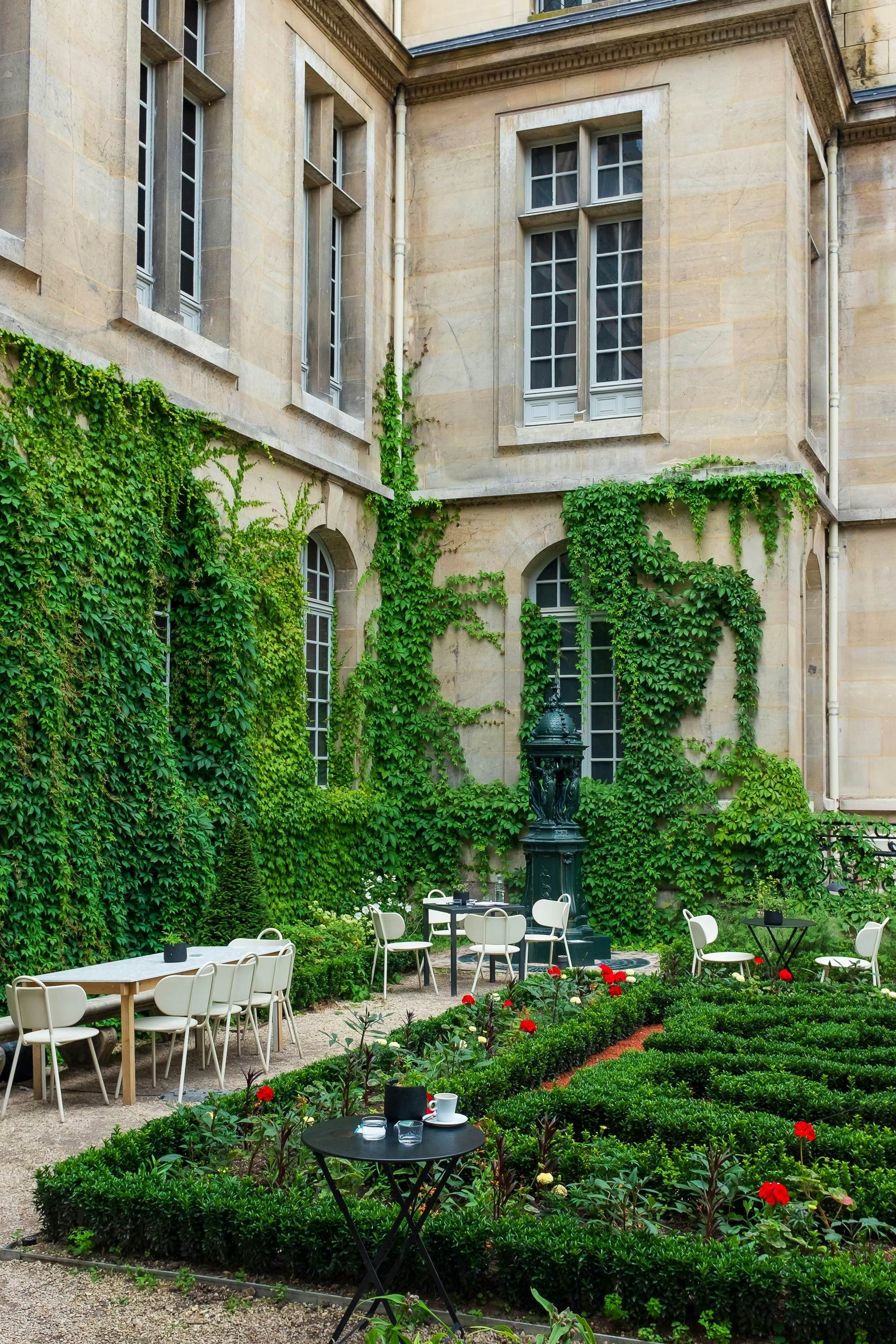 The vine-covered walls of the cour de la Victoire (Courtyard of the Victory) at the musée Carnavalet, with a fontaine Wallace in the background (vertical)