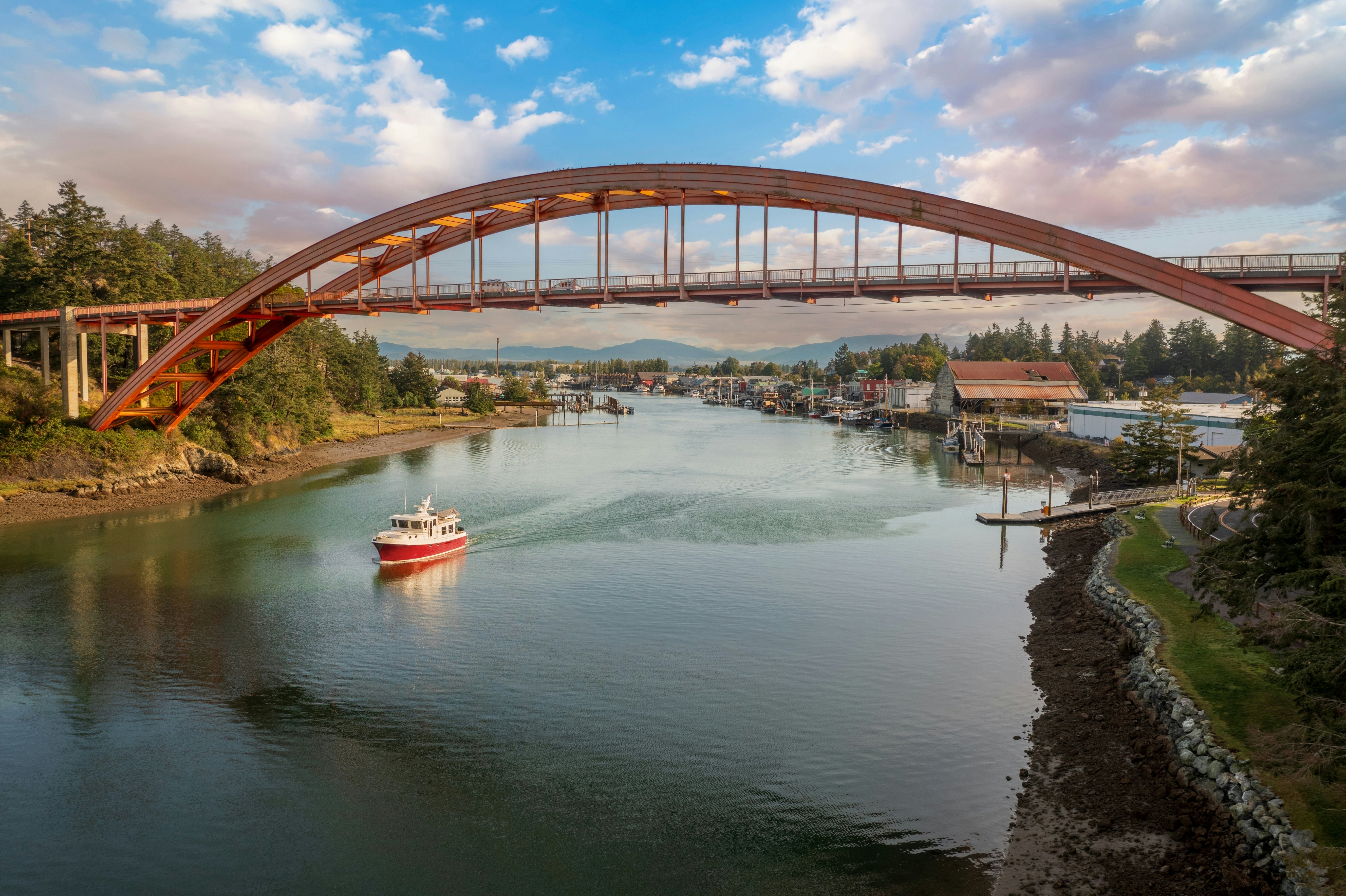 Historic Rainbow Bridge in the tourist town of La Conner, Washington with a boat passing underneath. The bridge connects the town to the island that is part of the Swinomish Reservation.