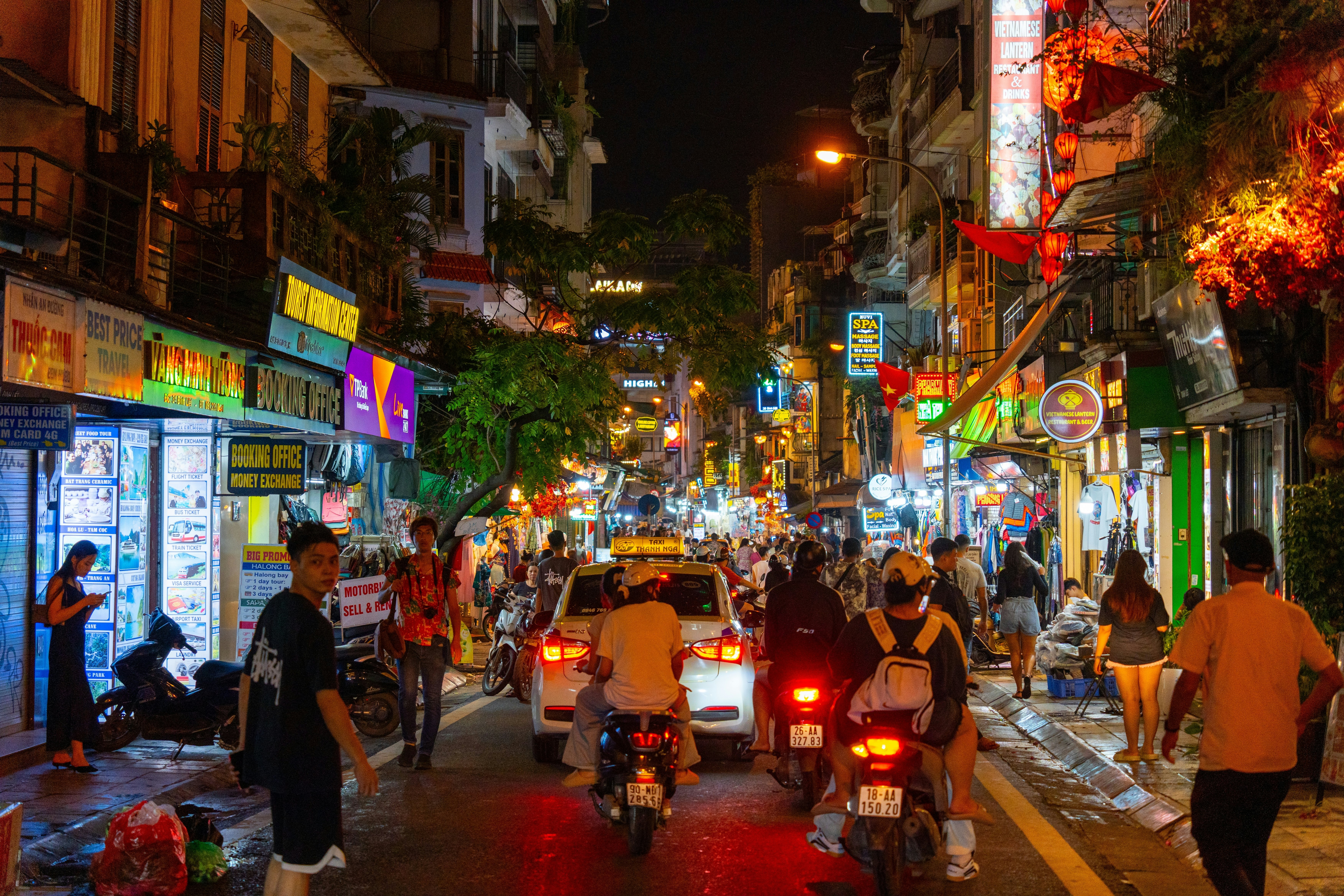 A night view of Hanoi Old Quarter Beer Street with pedestrians, bikers and lit-up shops