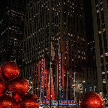 New York City - November 25, 2024: large Christmas spheres on a fountain, with the famous Radio City Music Hall building in the background, and its Christmas tree, located on Sixth Avenue, Manhattan, License Type: media, Download Time: 2025-11-18T21:44:55.000Z, User: adouglaslott59, Editorial: true, purchase_order: 65050 - Digital Destinations and Articles, job: Online editorial, client: Ultimate Christmas weekend in Manhattan, other: Ann Douglas Lott
