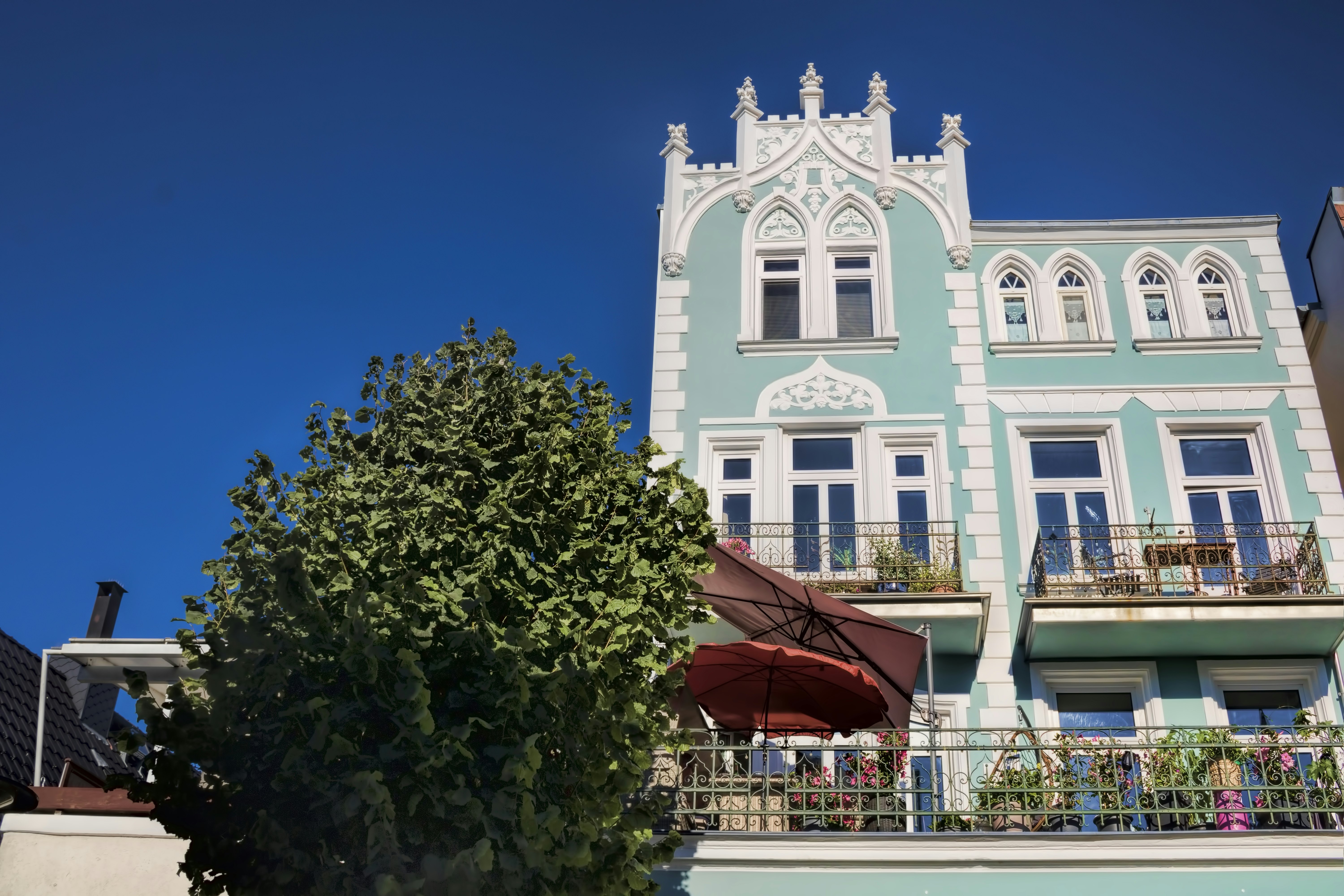A light green villa with ornate windows on a sunny day.