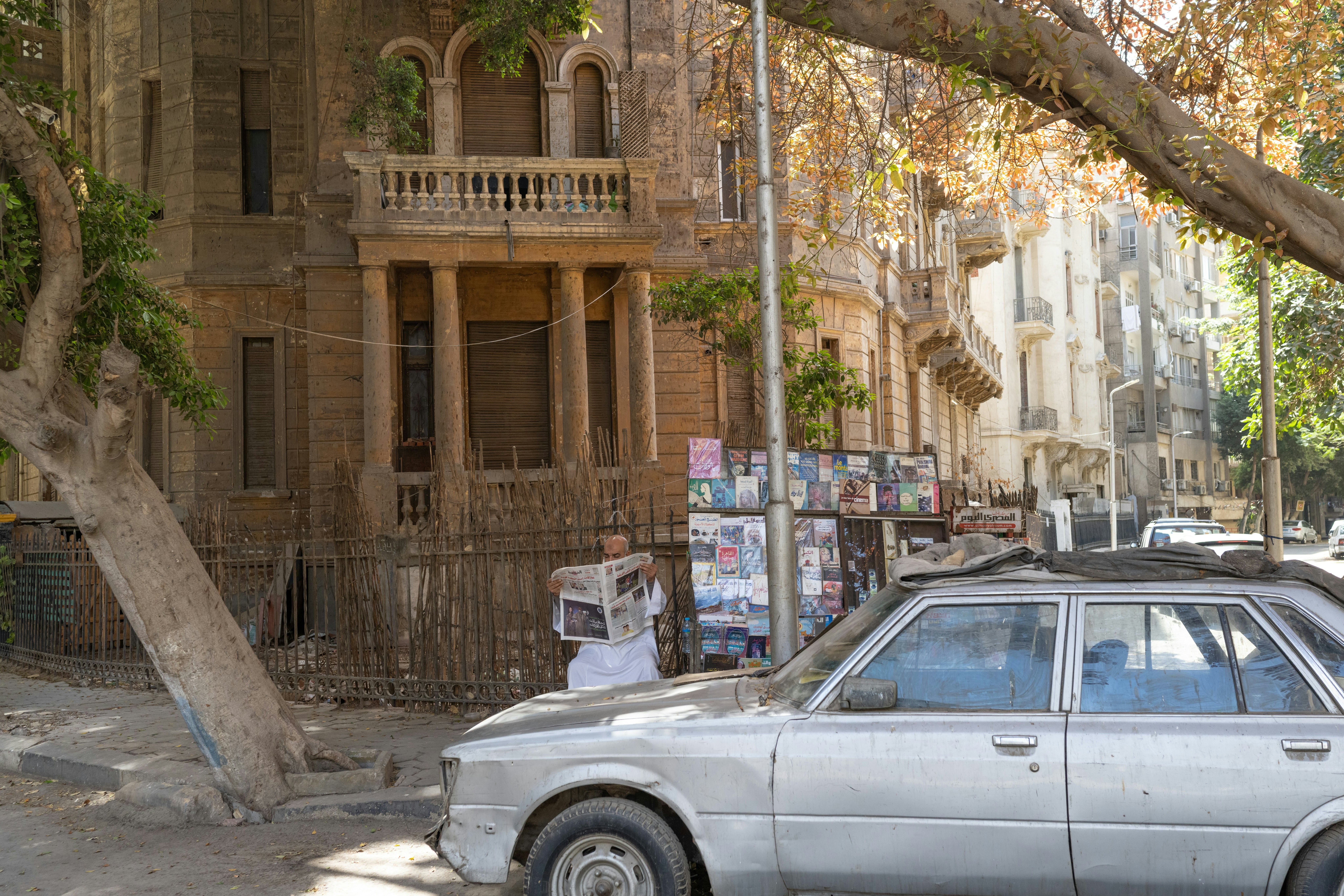 An old man reading an Egyptian newspaper beside his street stall selling books and magazines in the downtown neighborhood of Garden City, Cairo, Egypt