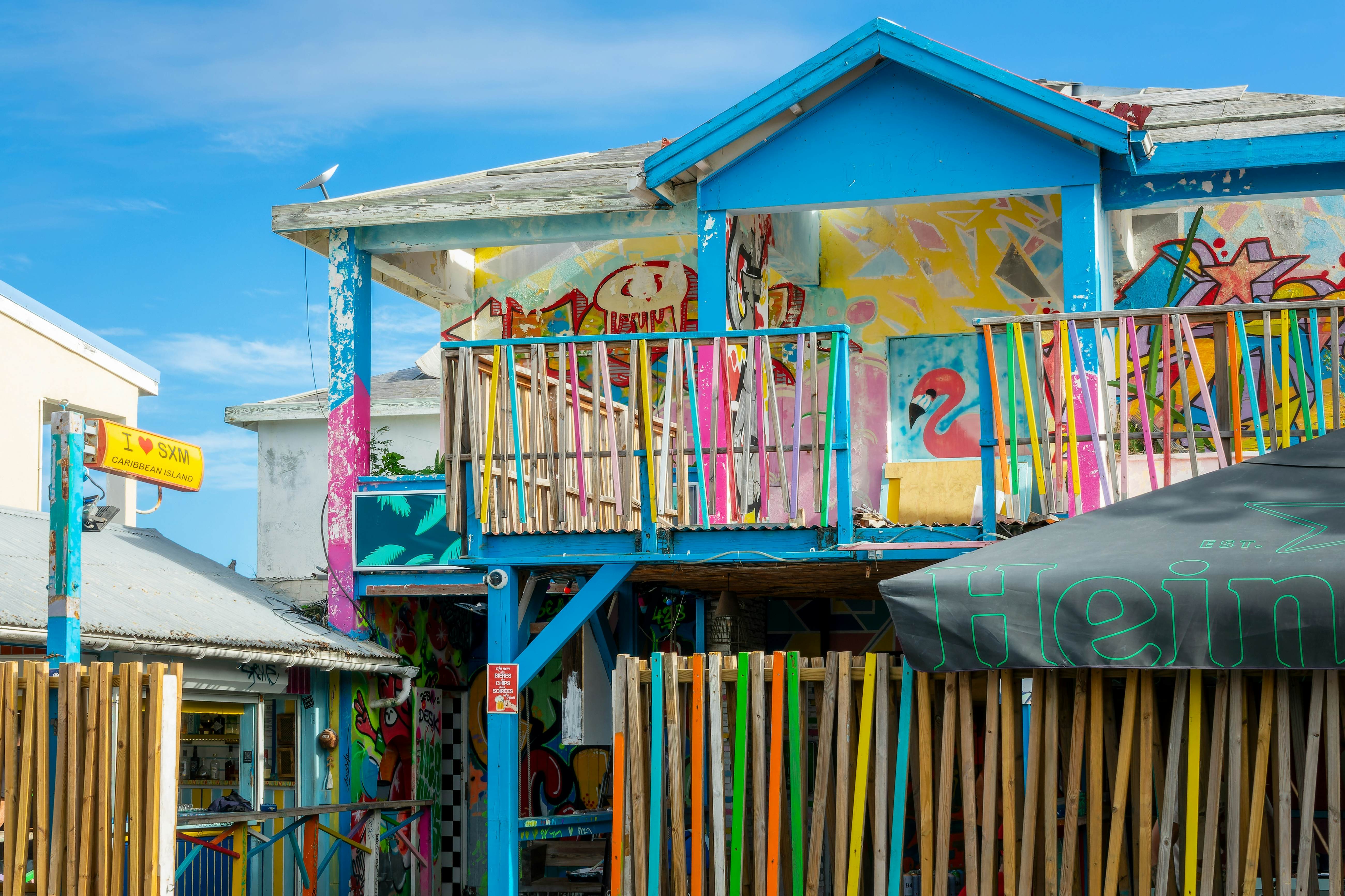A colorful building with various colored wooden slats along the fenceline and upper patio on a sunny day.