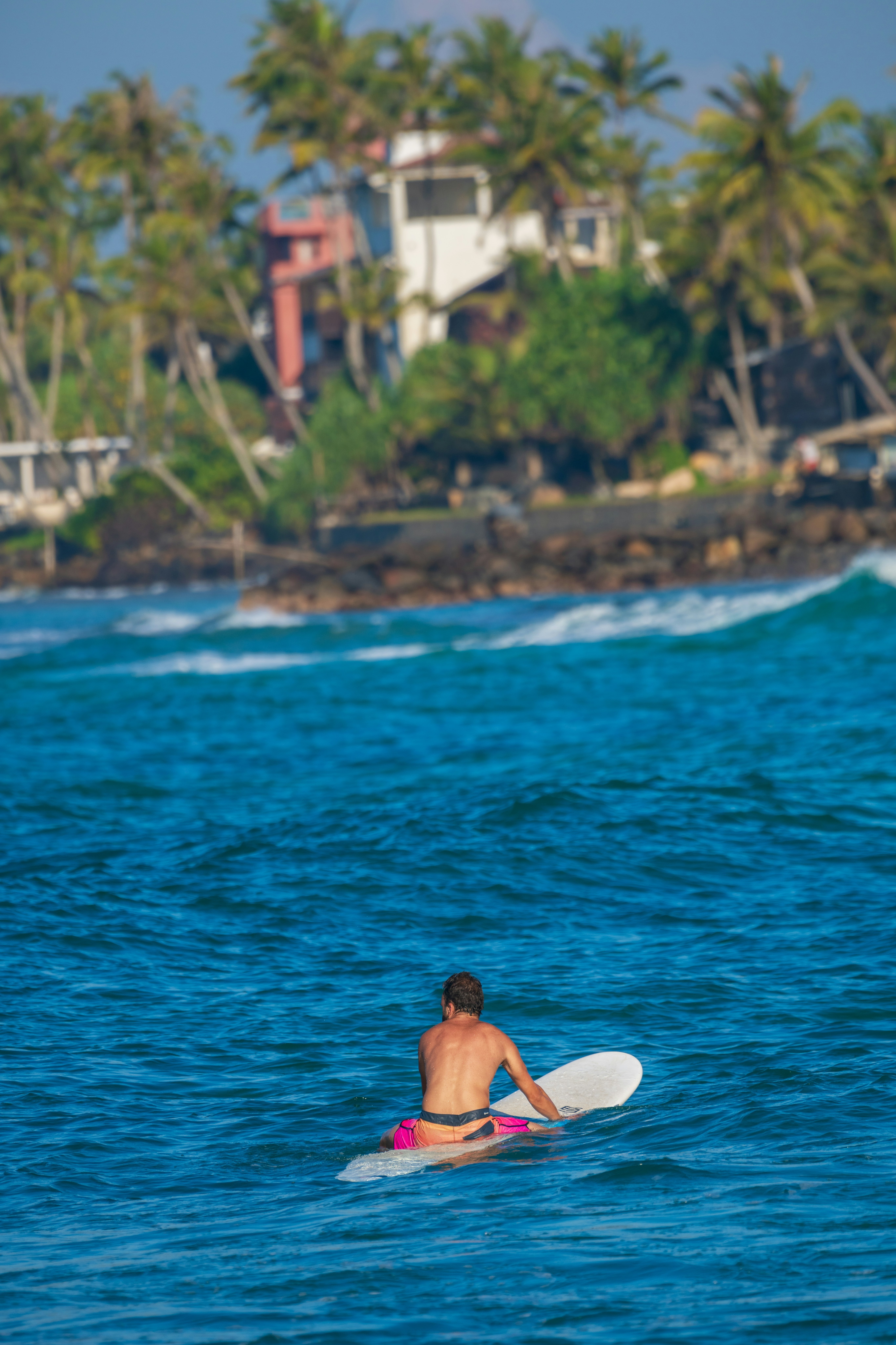 A man sits on his surfboard and waits for a wave.