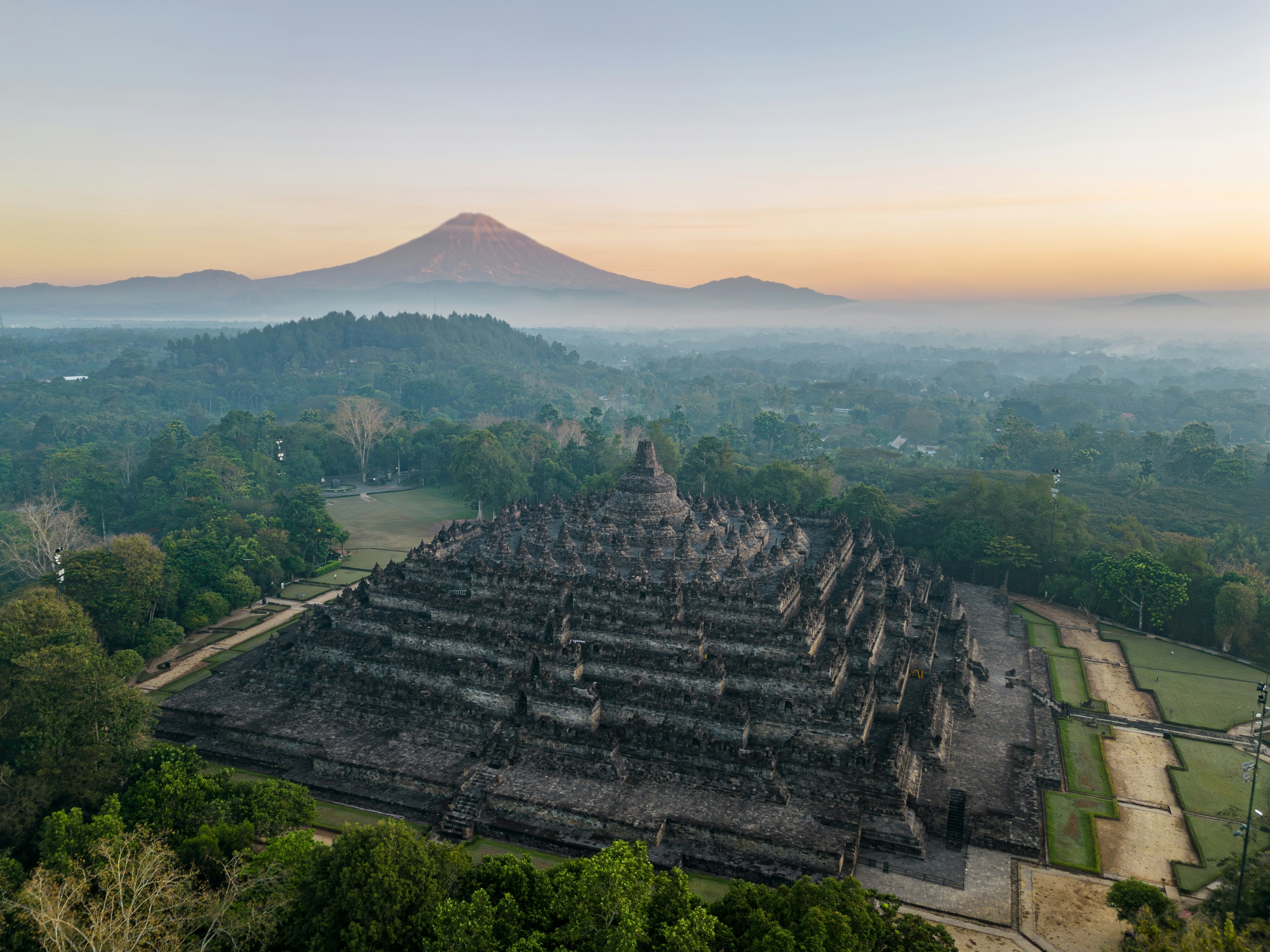 A view of Borobudur Temple in Java, Indonesia with the Merapi volcano in the background.