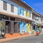Luang Prabang, Laos - November 22, 2025: Colorful colonial-style street in Southeast Asia with people walking, scooters, and tuk-tuks on a sunny day., License Type: media, Download Time: 2025-11-25T19:03:00.000Z, User: Malecia.Elamin_Lonelyplanet, Editorial: true, purchase_order: 65050 - Digital Destinations and Articles, job: Online editorial, client: Guide to Luang Prabang, Laos, other: Malecia Walker