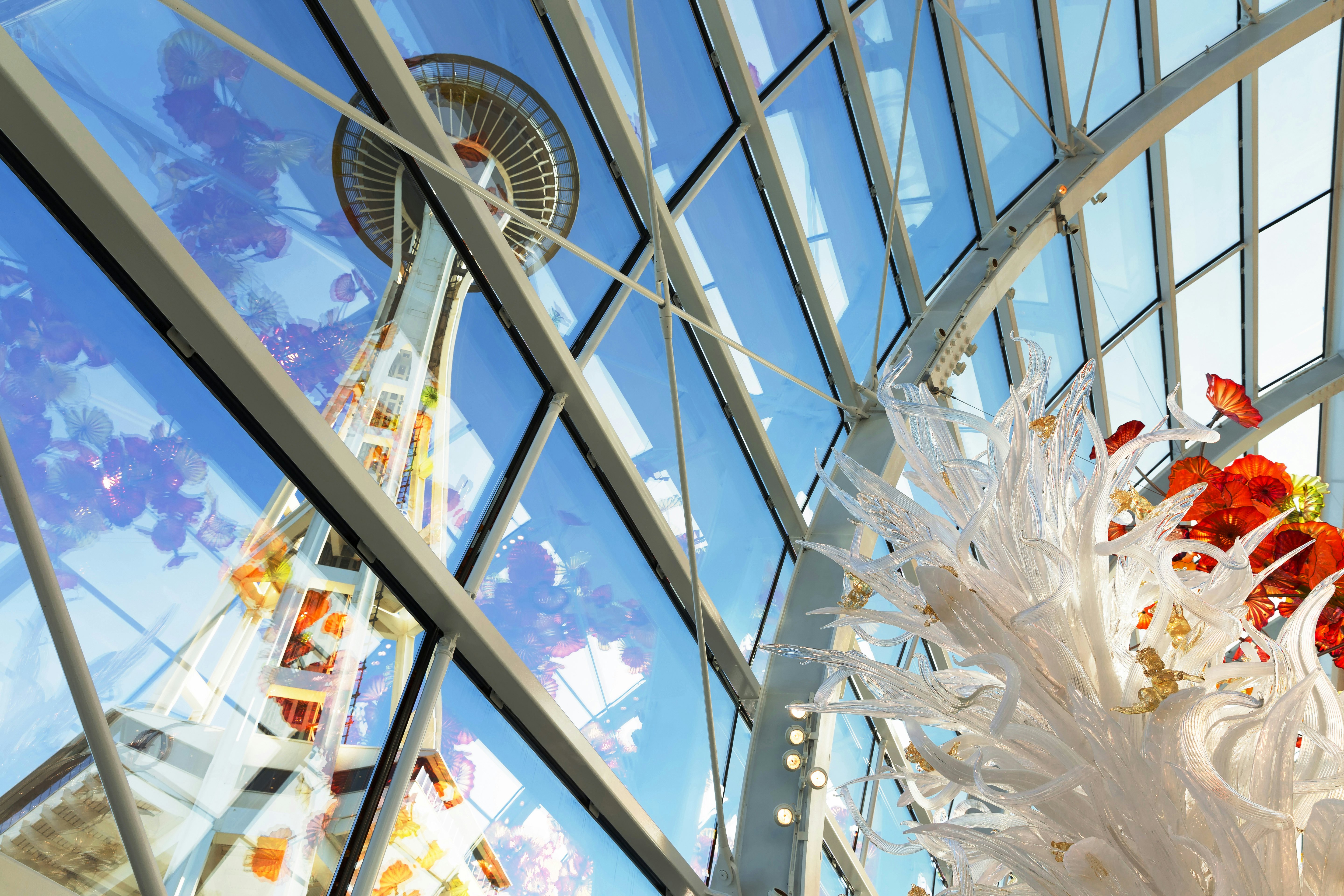 View of the Space Needle from inside the Chihuly Garden and Glass museum conservatory next door. Unique perspective. Reflections. Focus is on the glass sculpture in the foreground.