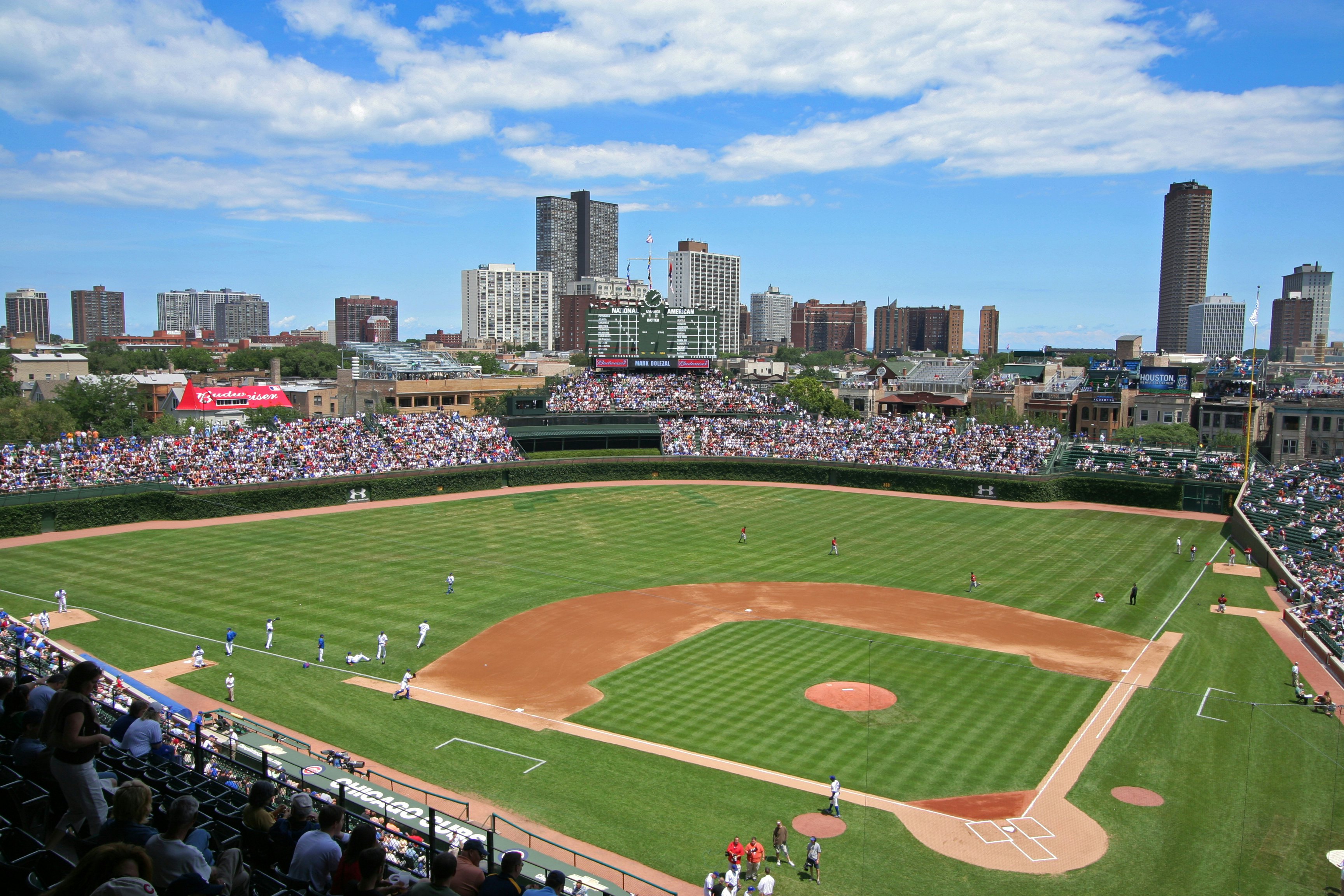 A baseball game in a stadium. The seats are full of spectators.