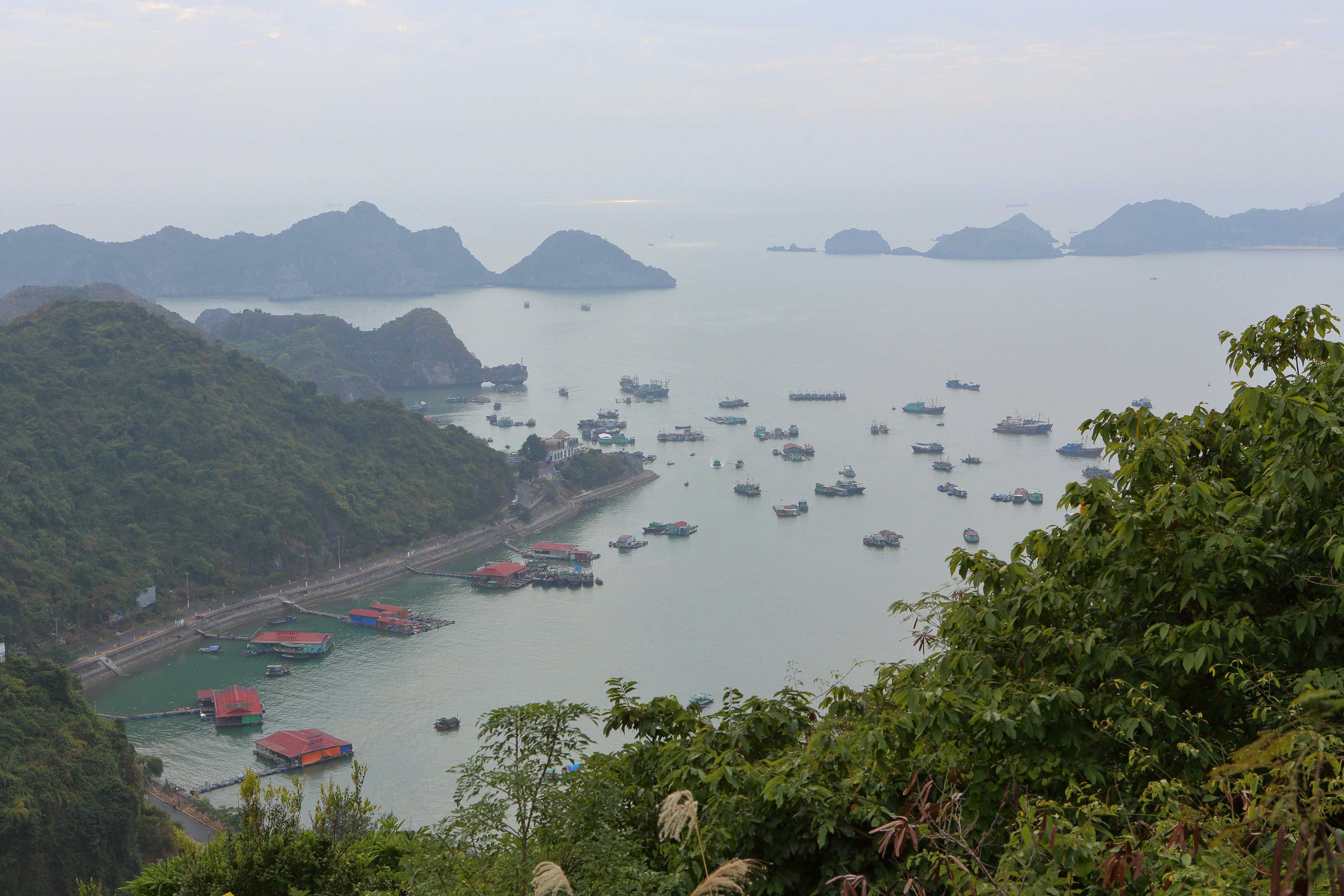Multiple boats are in the waters near hills poking out of the water
